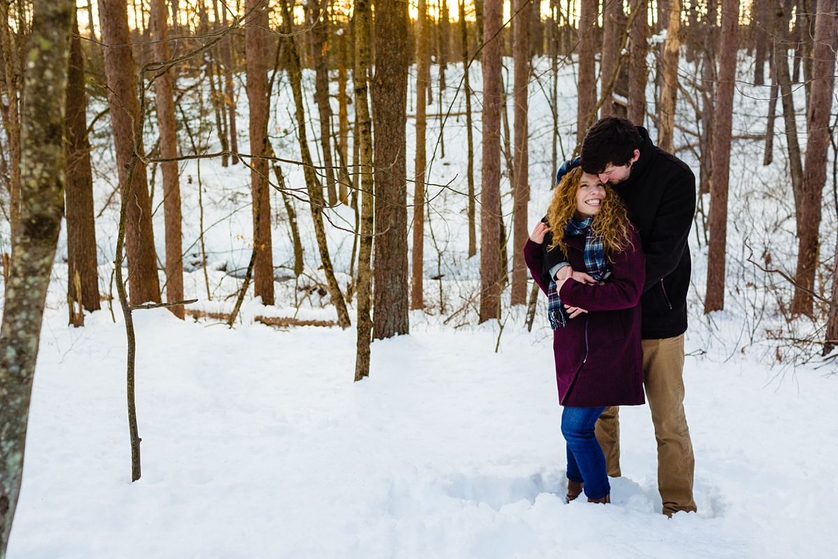 Engagement Session in winter with the smiling couple deep in the snow and woods at Fells Reservation with their Maine Wedding Photographer
