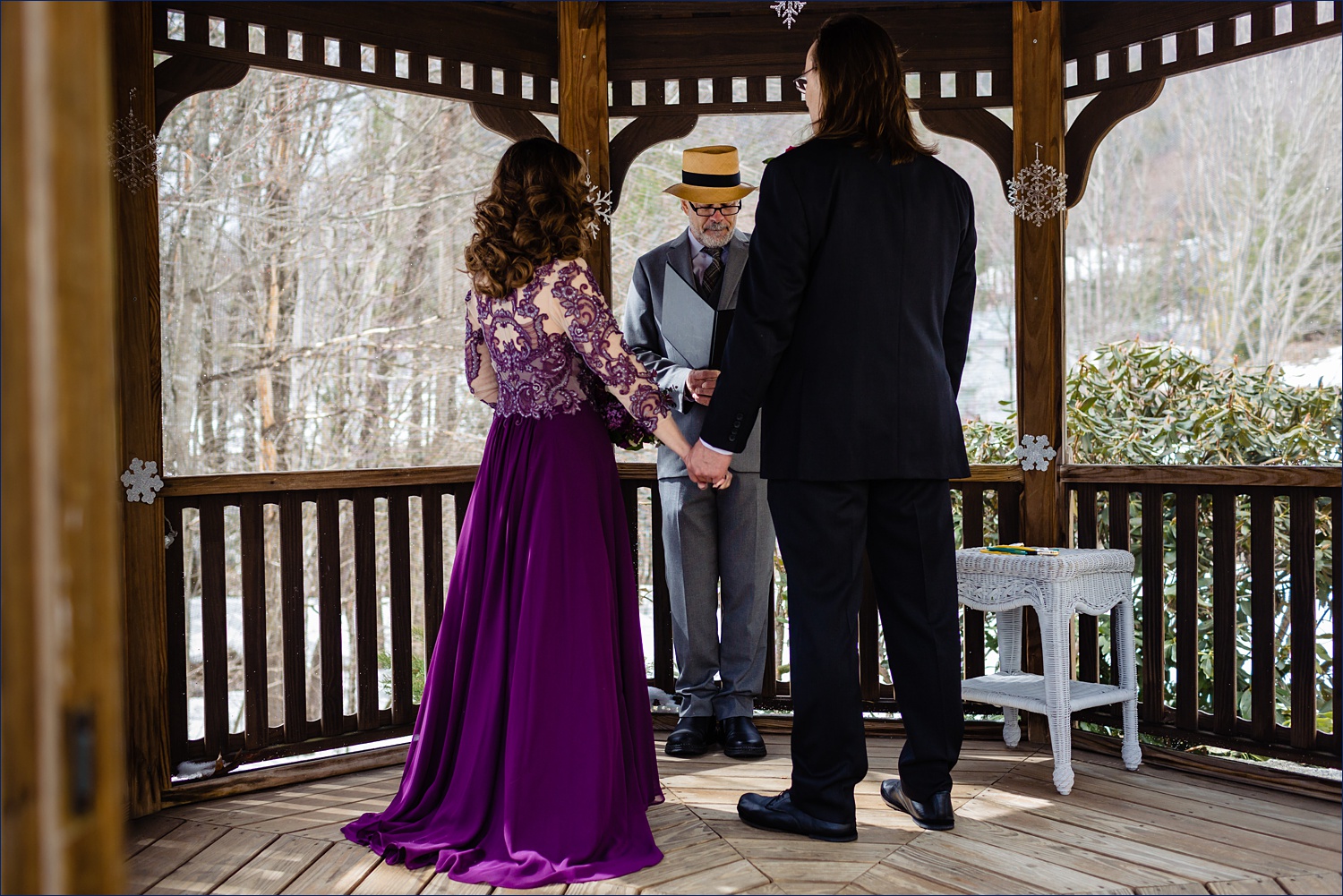 The bride and groom hold hands during their elopement ceremony outside in spring - the bride wears a purple dress