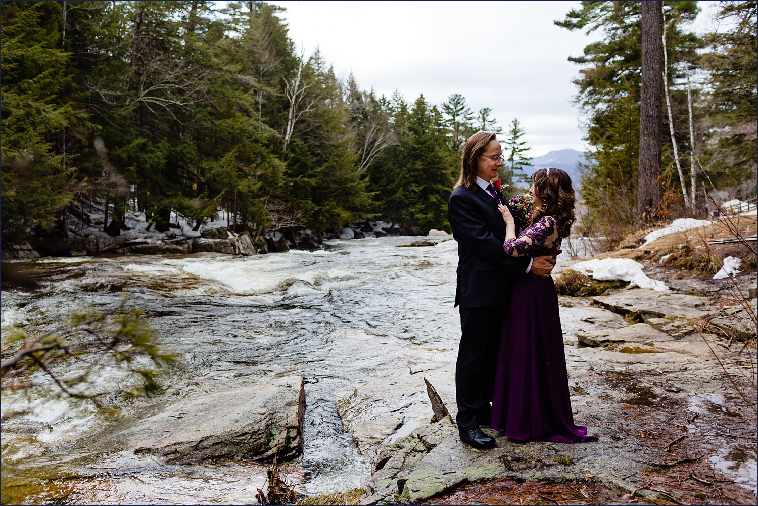 The newlyweds stand by Jackson Falls in the Spring chill air after their NH Elopement