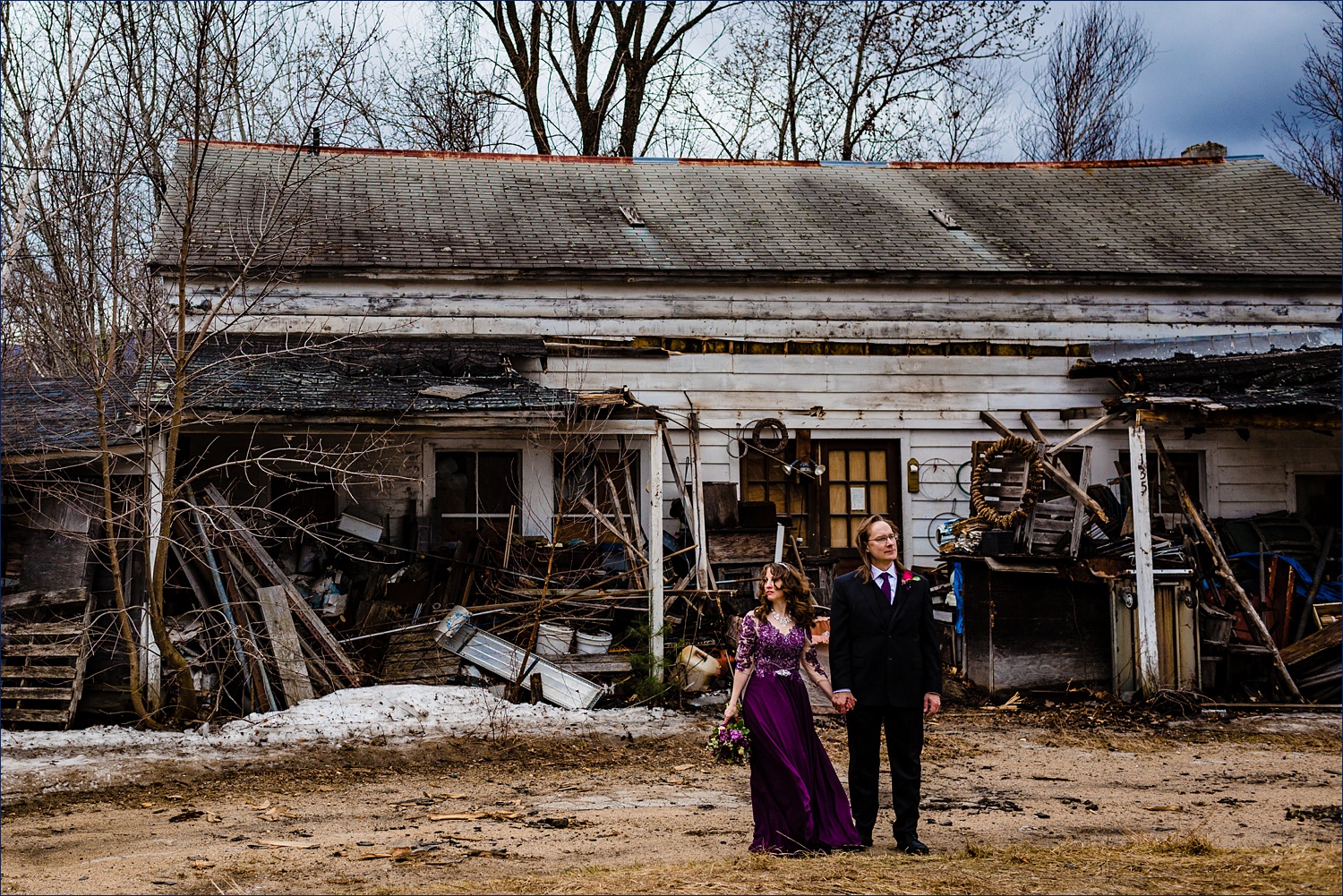The newlyweds stand in front of a run down home along the road in Jackson, NH after eloping