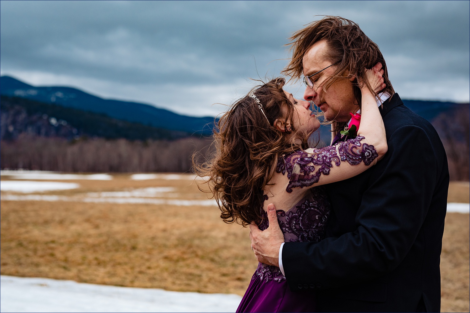 The groom holds tight to his bride as they keep each other warm in the snowy White Mountains after they eloped in New Hampshire