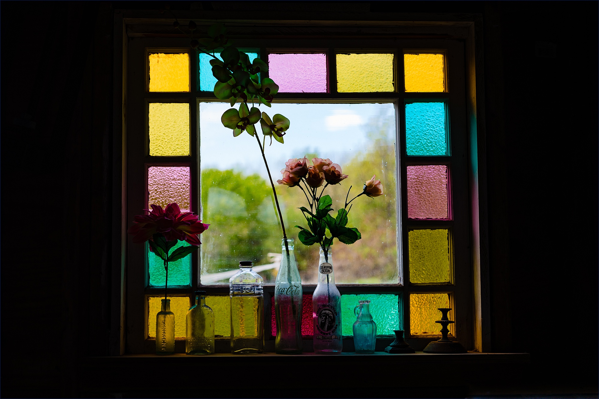 Flowers decorate the farmhouse's stained glass windows on the wedding day