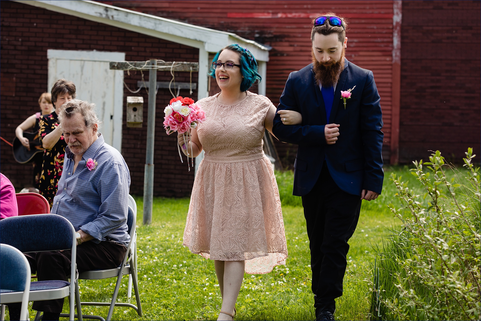 The bride's brother escorts her into the outdoor Maine intimate wedding ceremony