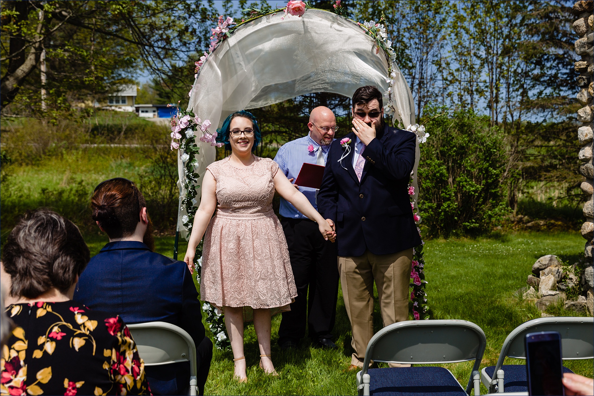 The groom wipes a tear after officially marrying his bride in the intimate Maine backyard wedding