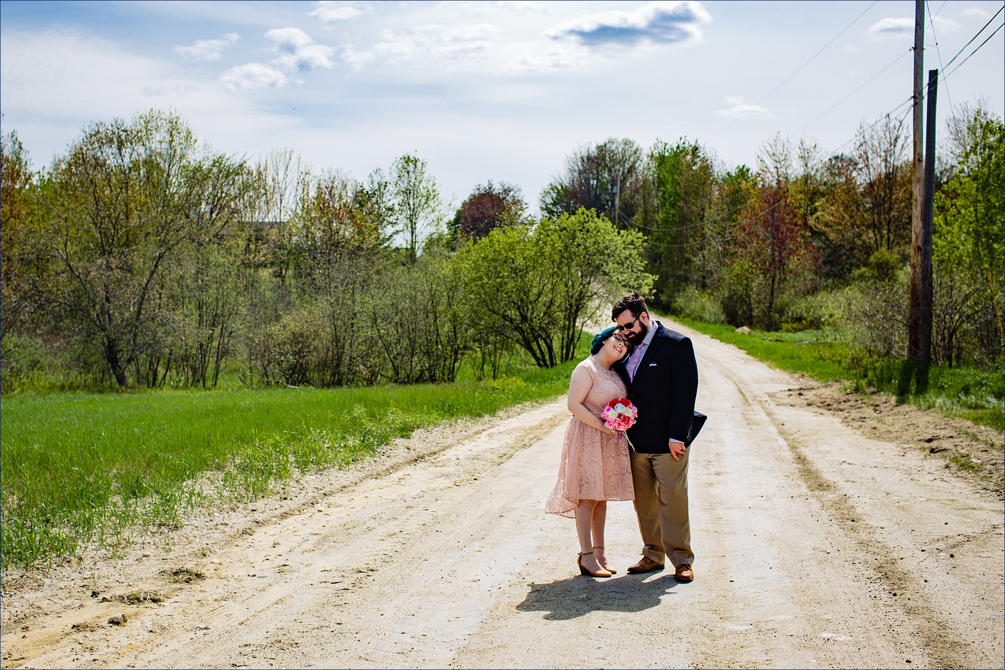 The bride and groom hold tight to one another on a Maine dirt road after officially being wed at home with family