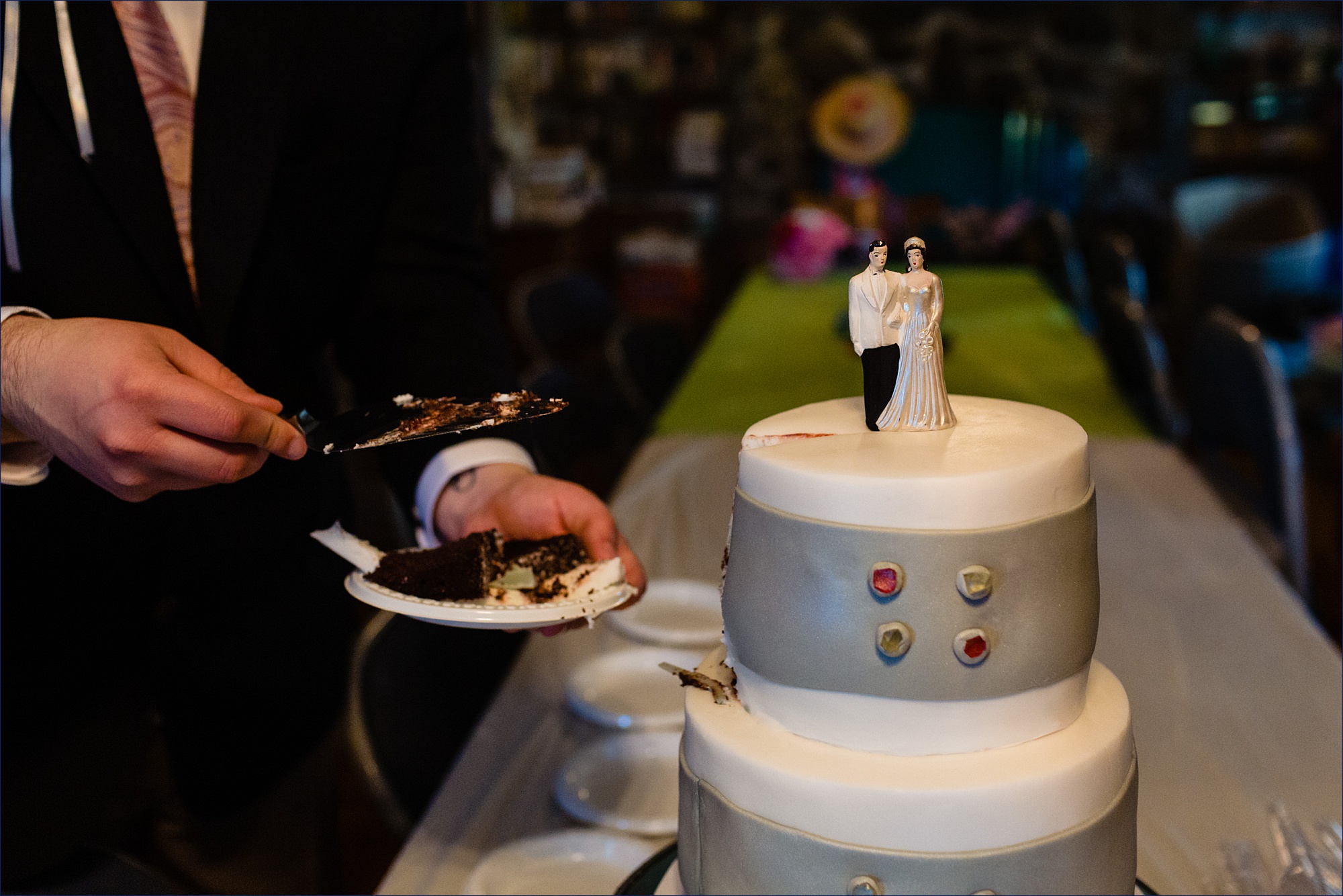 The groom cuts into the wedding cake in the Maine farmhouse living room