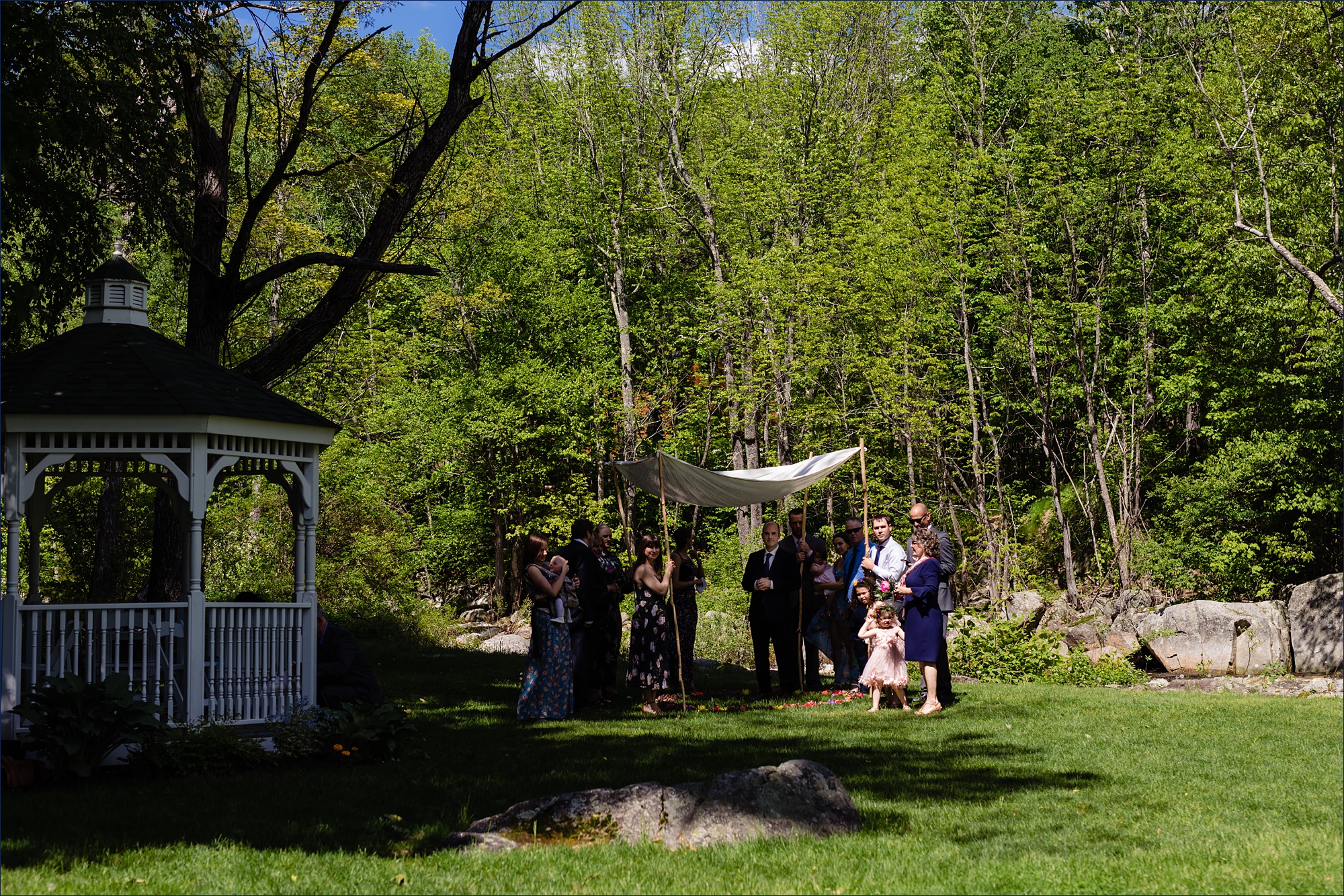 The family and the groom wait under the chuppah for the bride to arrive to their White Mountain wedding