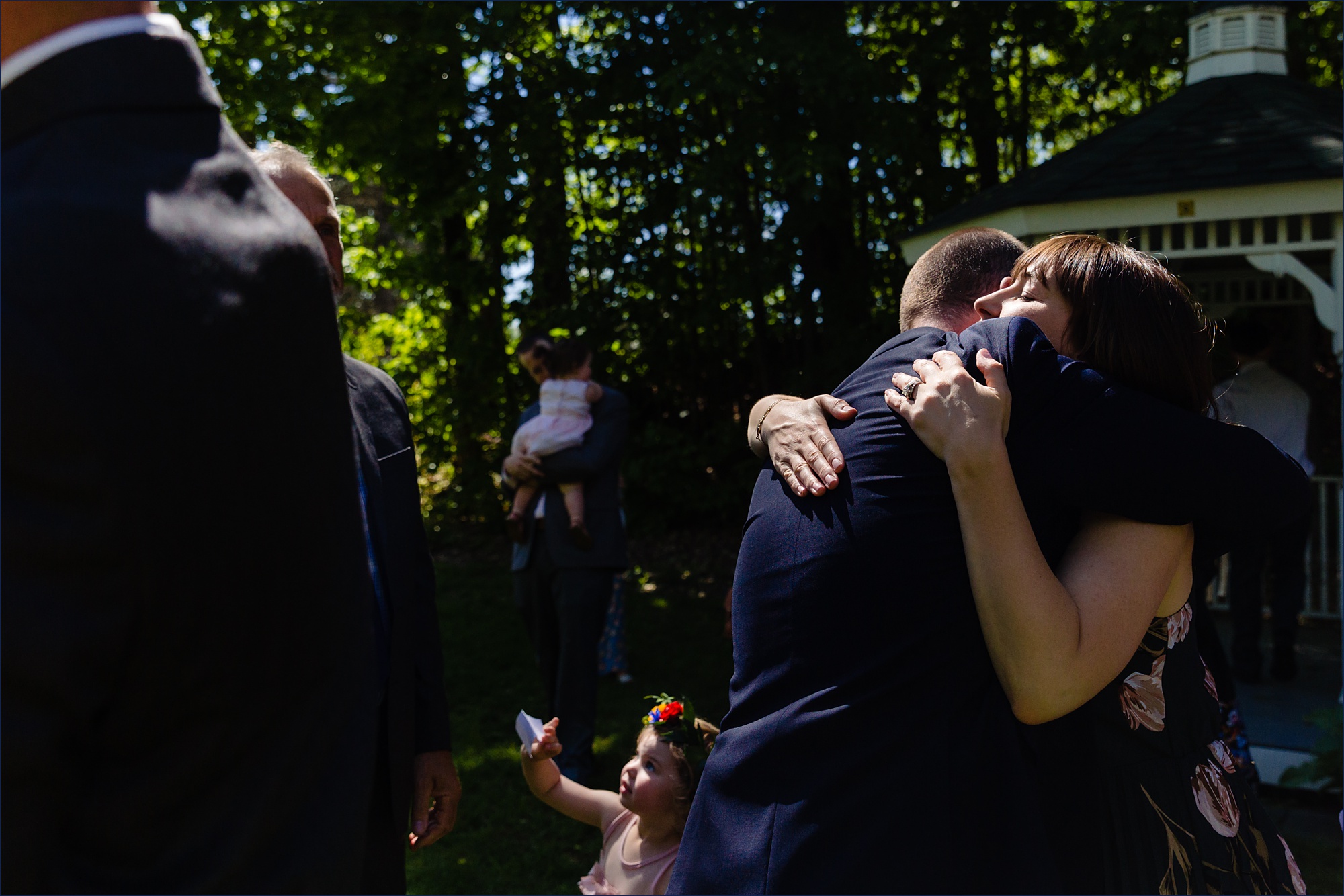 The groom hugs his sister after his outdoor wedding day in the sun