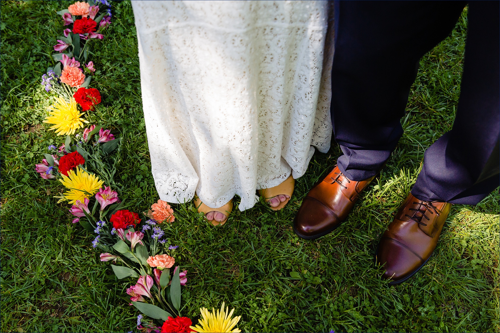 The bride and groom stand in the circle of flowers laid out for their chuppah in Jackson, NH