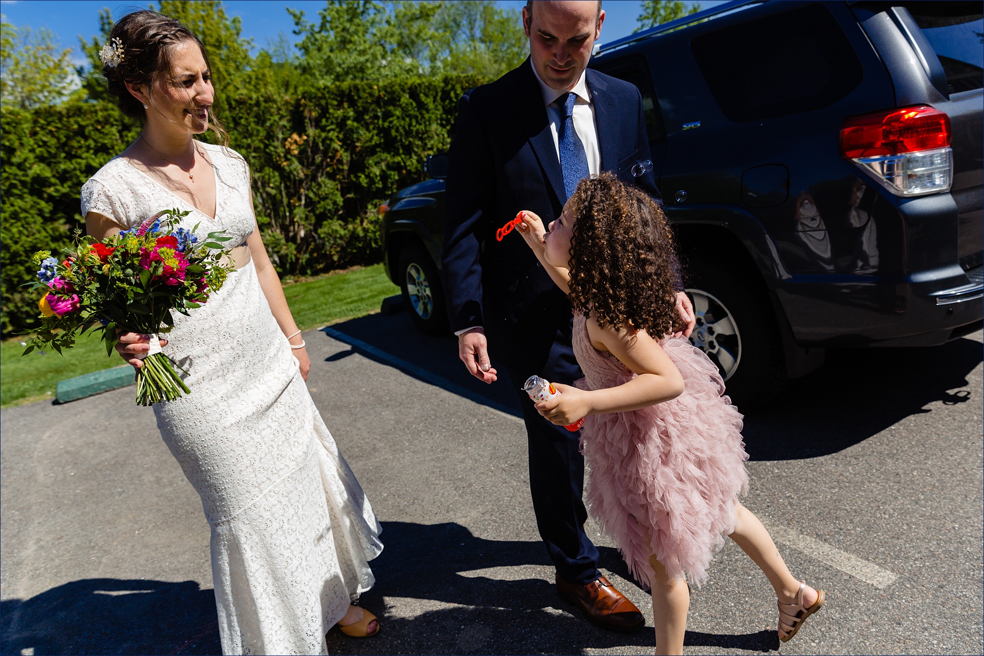 The flower girl blows celebratory bubbles at the newlyweds outside their wedding ceremony