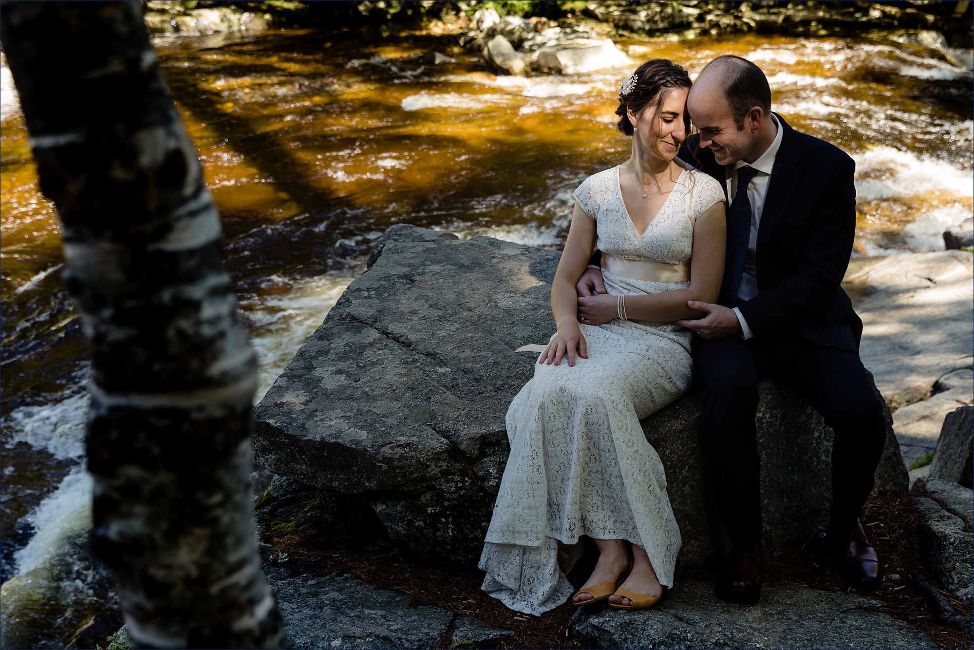 The newlyweds sit close together on the rocks in the White Mountains after eloping in NH