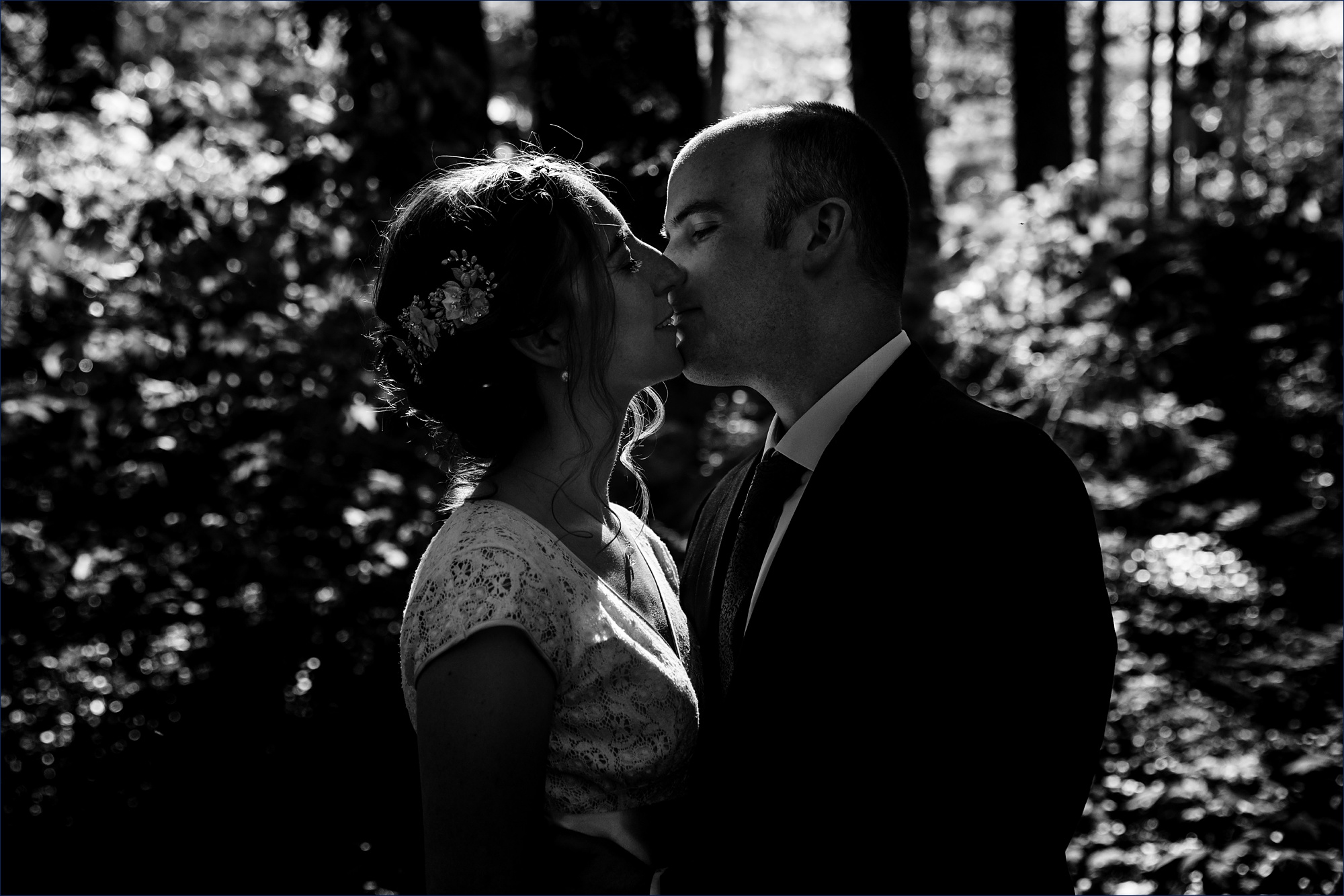 The bride and groom kiss one another in the woods of New Hampshire after their ceremony
