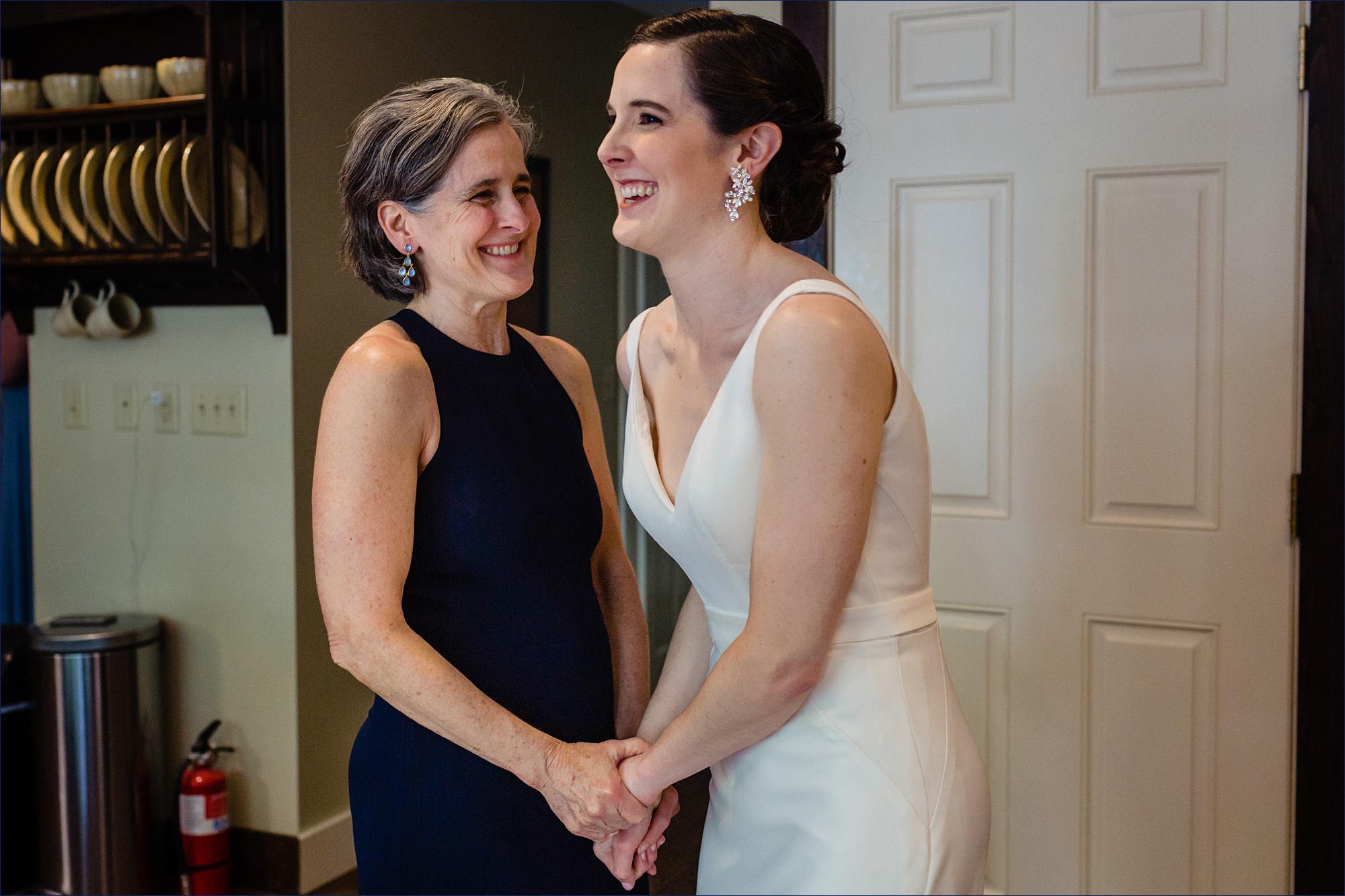 The bride and her mom laugh with one another before the wedding ceremony is going to begin