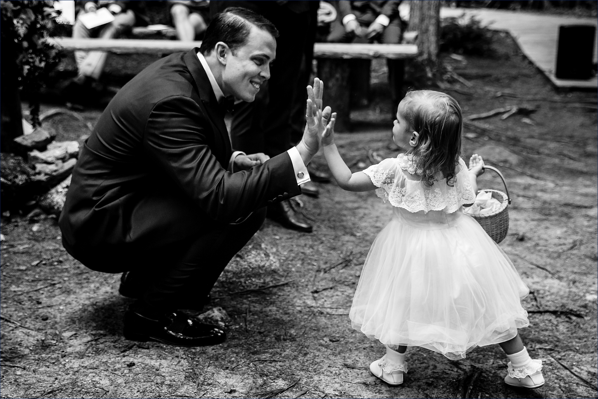 The flower girl and the groom high five at the wedding ceremony in the woods of Maine