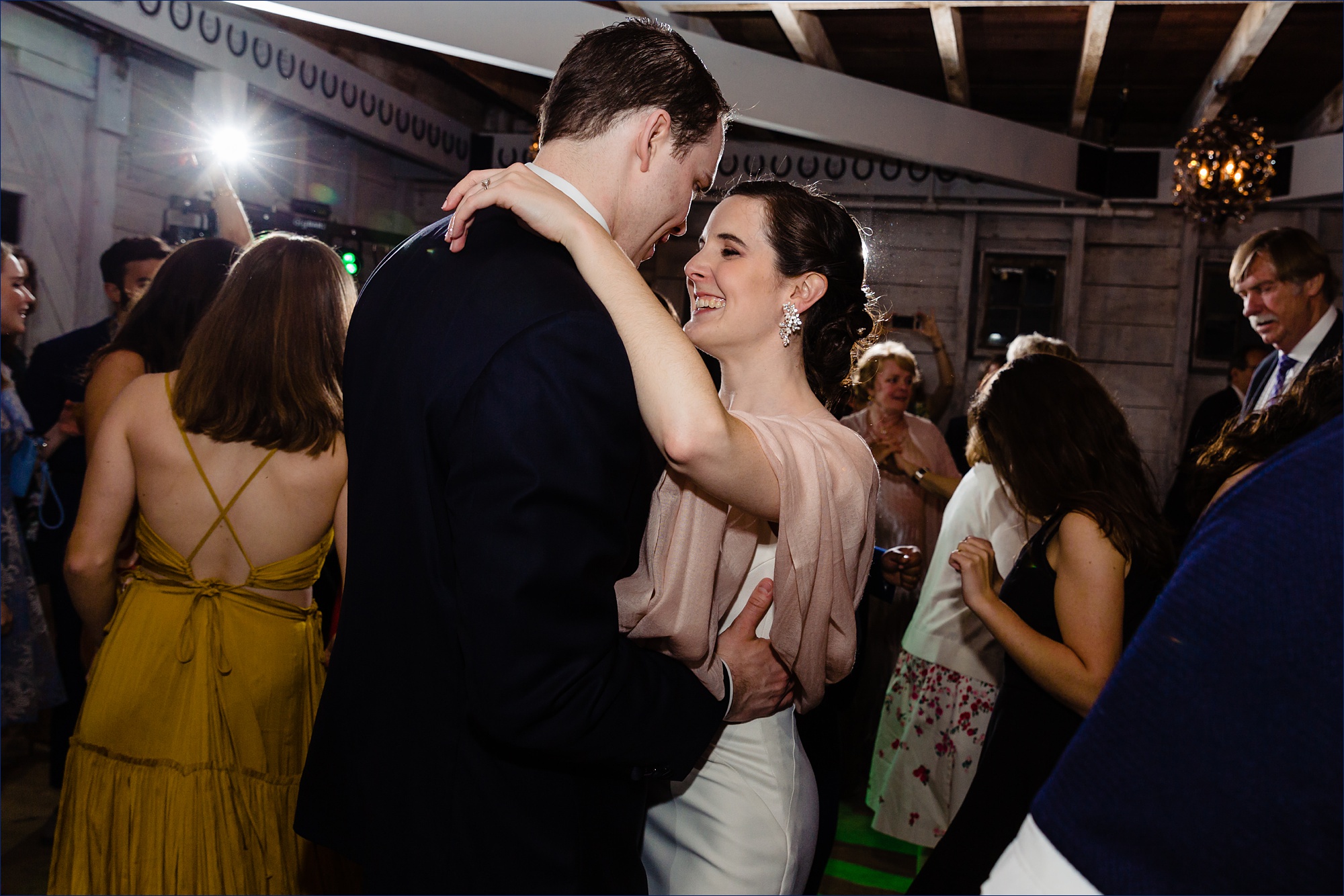 The bride and groom dance at their wedding reception in the barn and are full of smiles