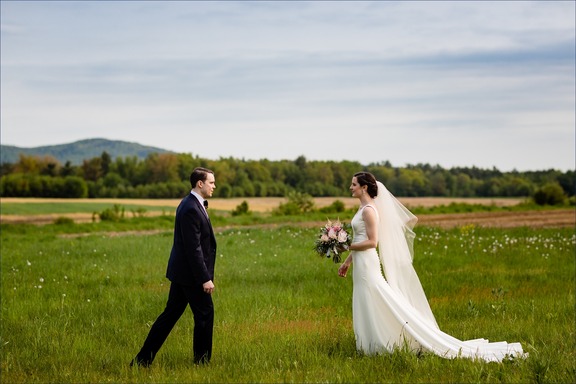 Hardy Farm wedding with the bride and groom approaching one another in a field in front of the White Mountains