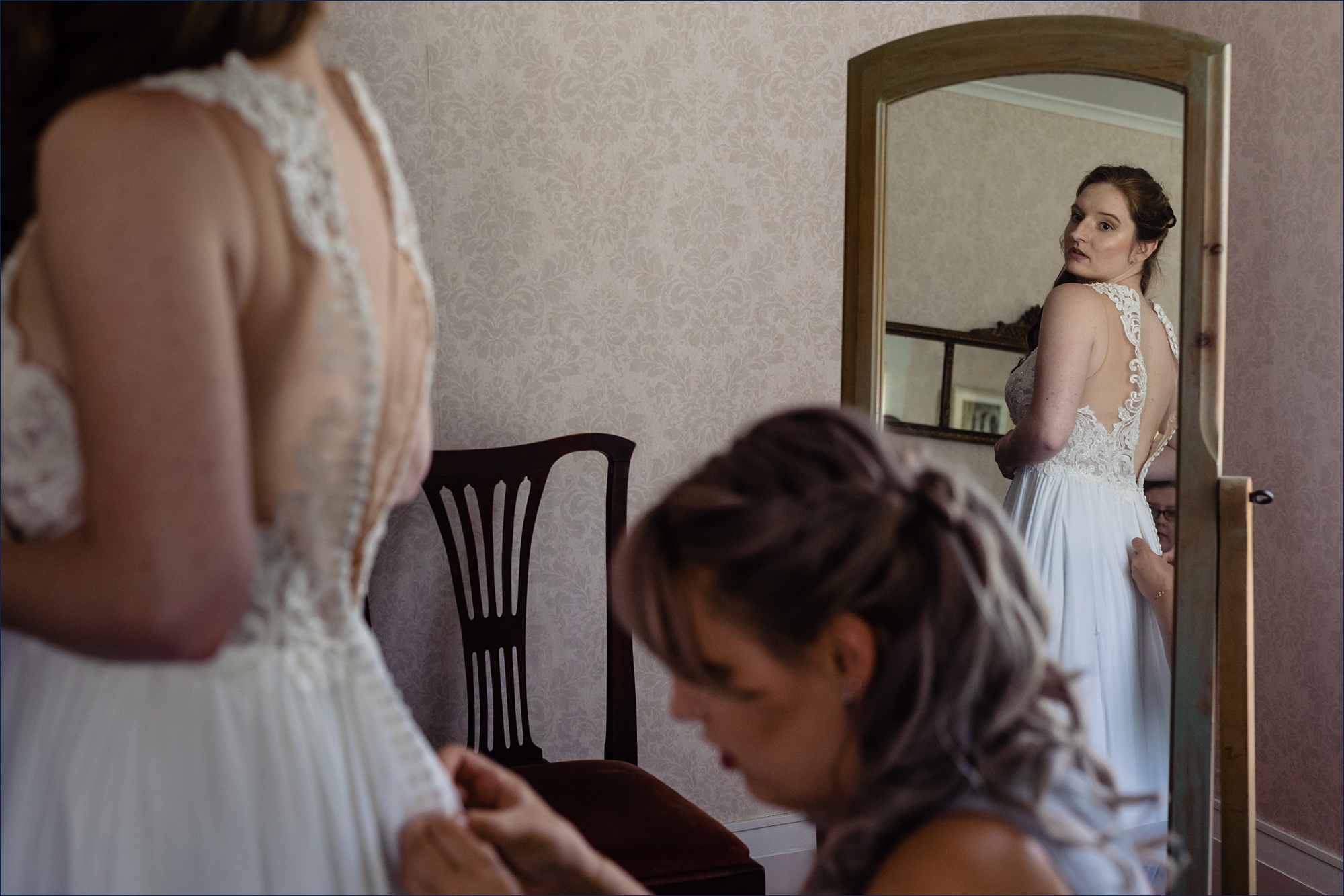 The bride gets buttoned into her wedding gown in the farmhouse at Kitz Farm