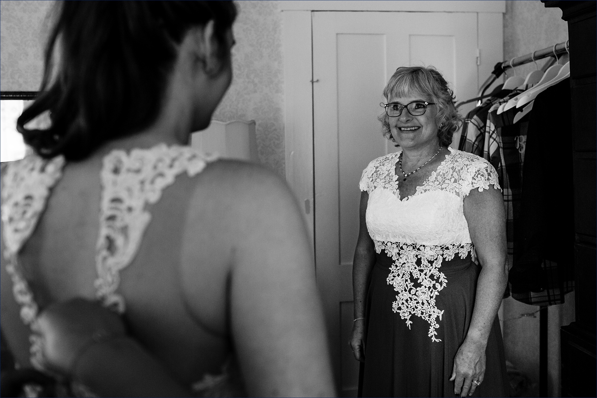 The mother of the bride watches as her daughter gets into her wedding gown with love in her eyes