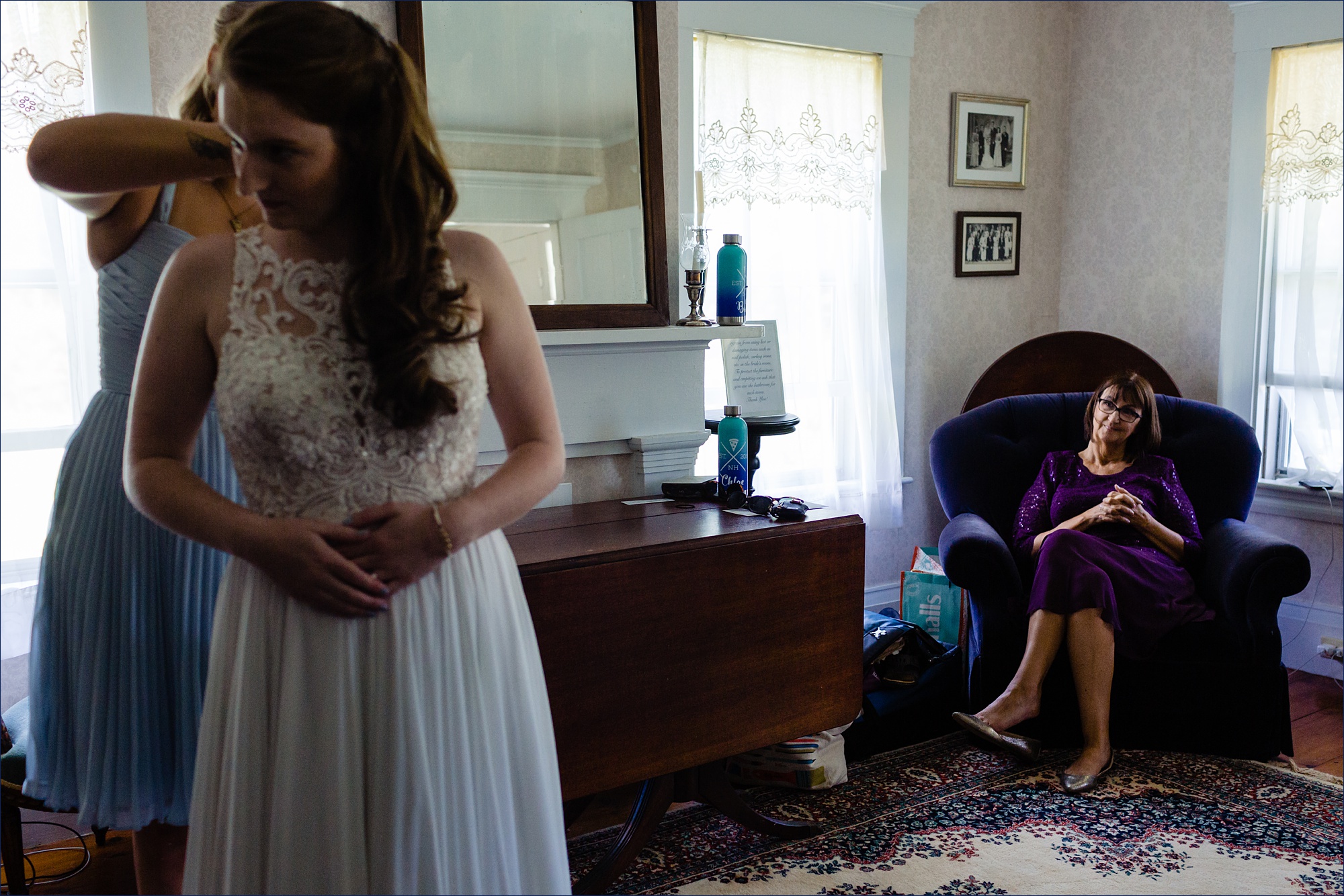 Mother of the groom watches as the bride gets the final touches on her wedding day attire