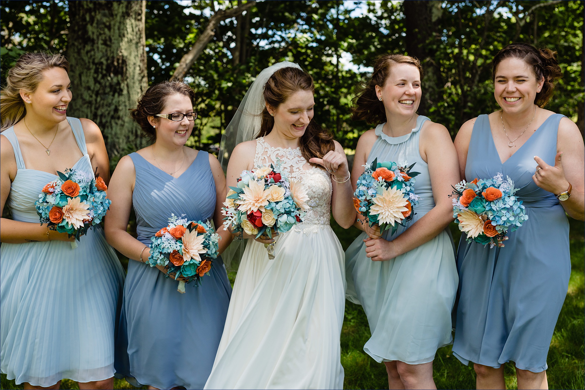 The bridesmaids and bride all laugh and get playful in the trees at Kitz Farm