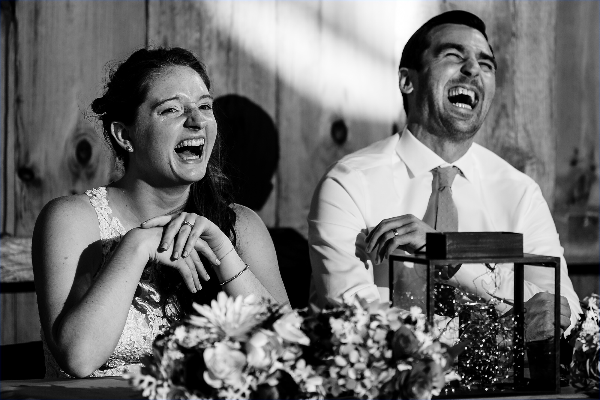 The bride and groom laugh at toasts at their wedding reception