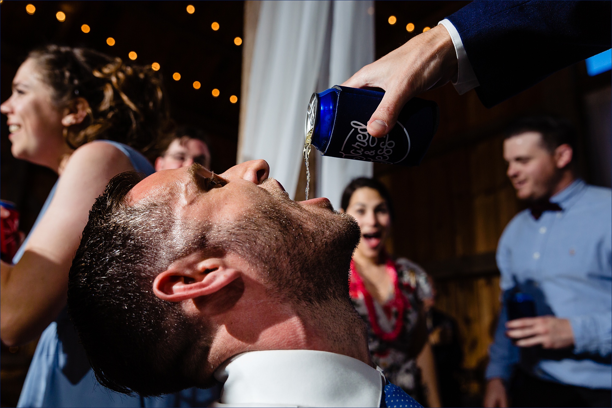One of the groomsmen gets a tasty beer poured into his mouth at the New Hampshire wedding reception