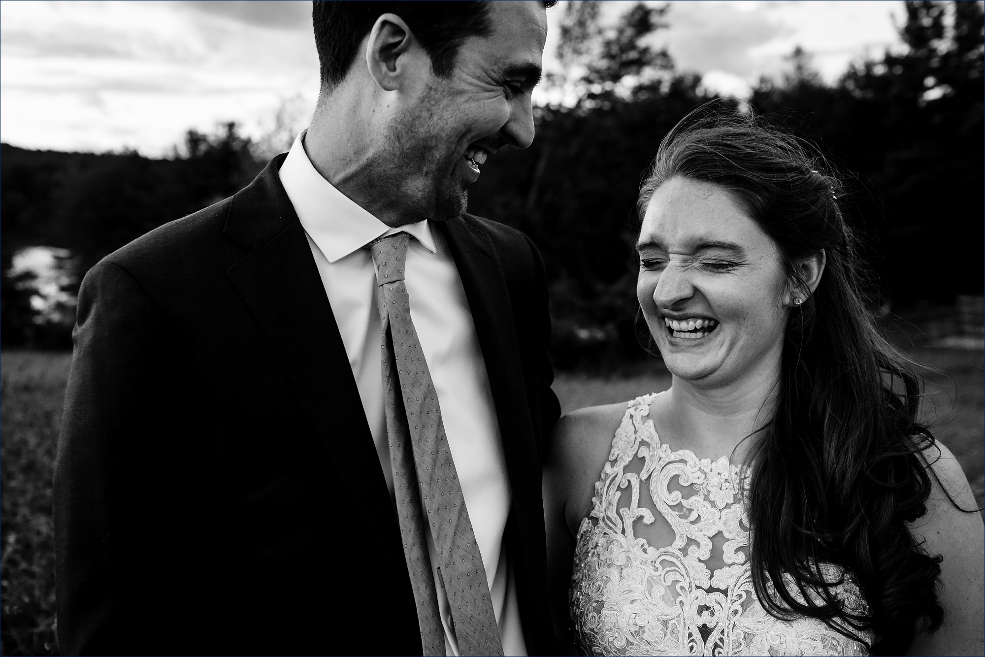 The bride cracks up at a joke from the groom in the golden hour at their NH wedding day