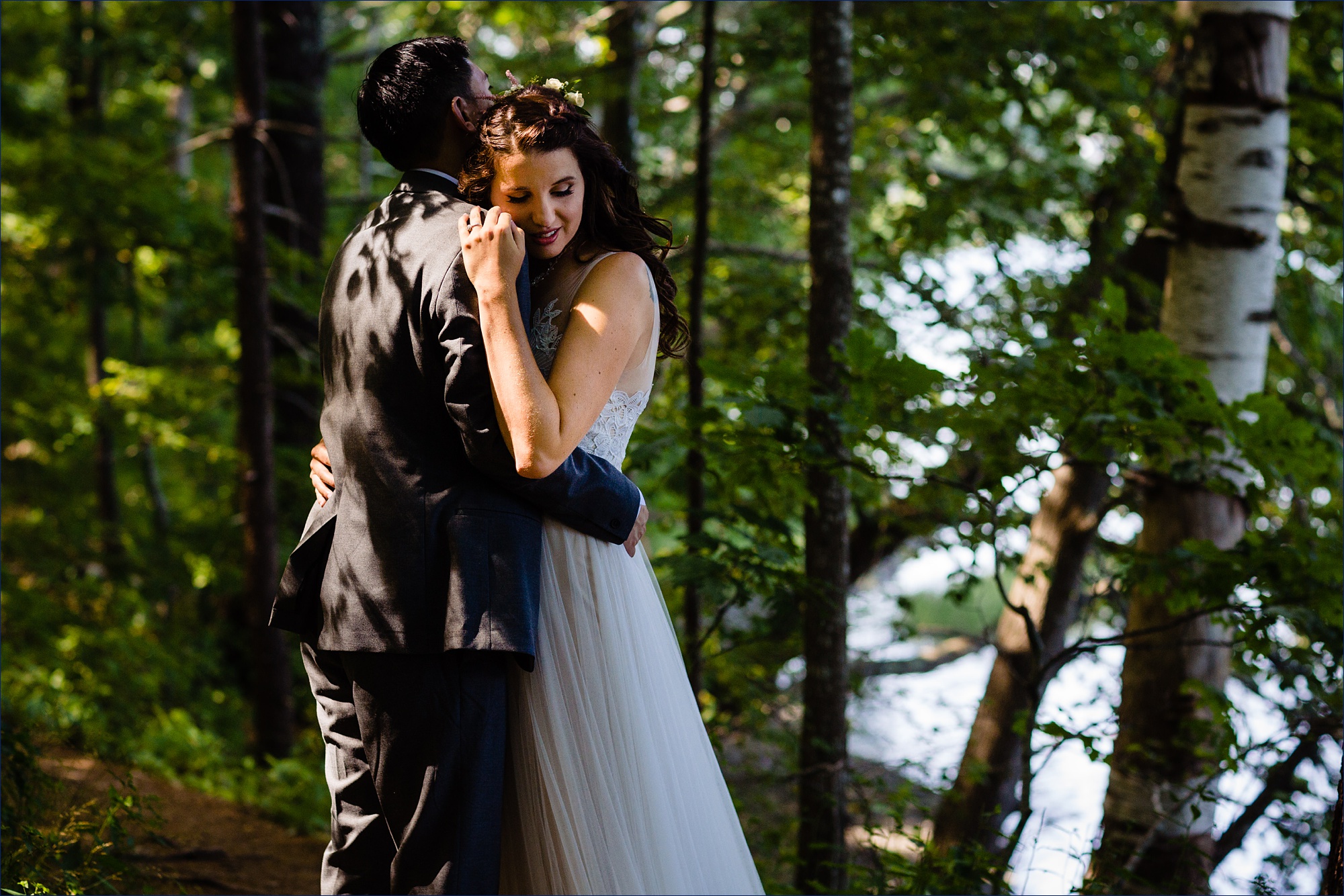 The bride and groom hug one another in the woods on their York Maine Wedding day