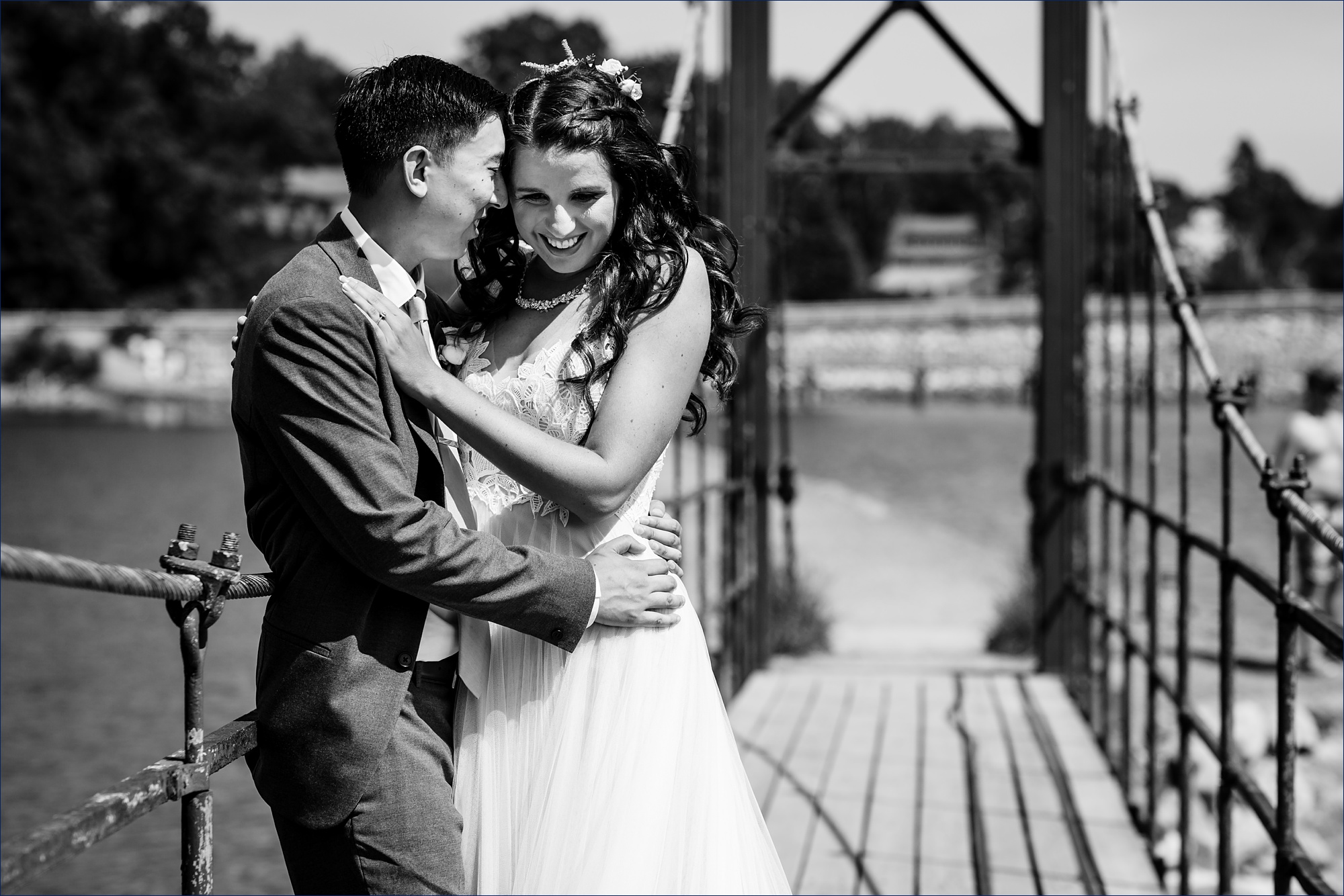 The groom makes the bride laugh in the sun while standing on the Wiggly Bridge in York