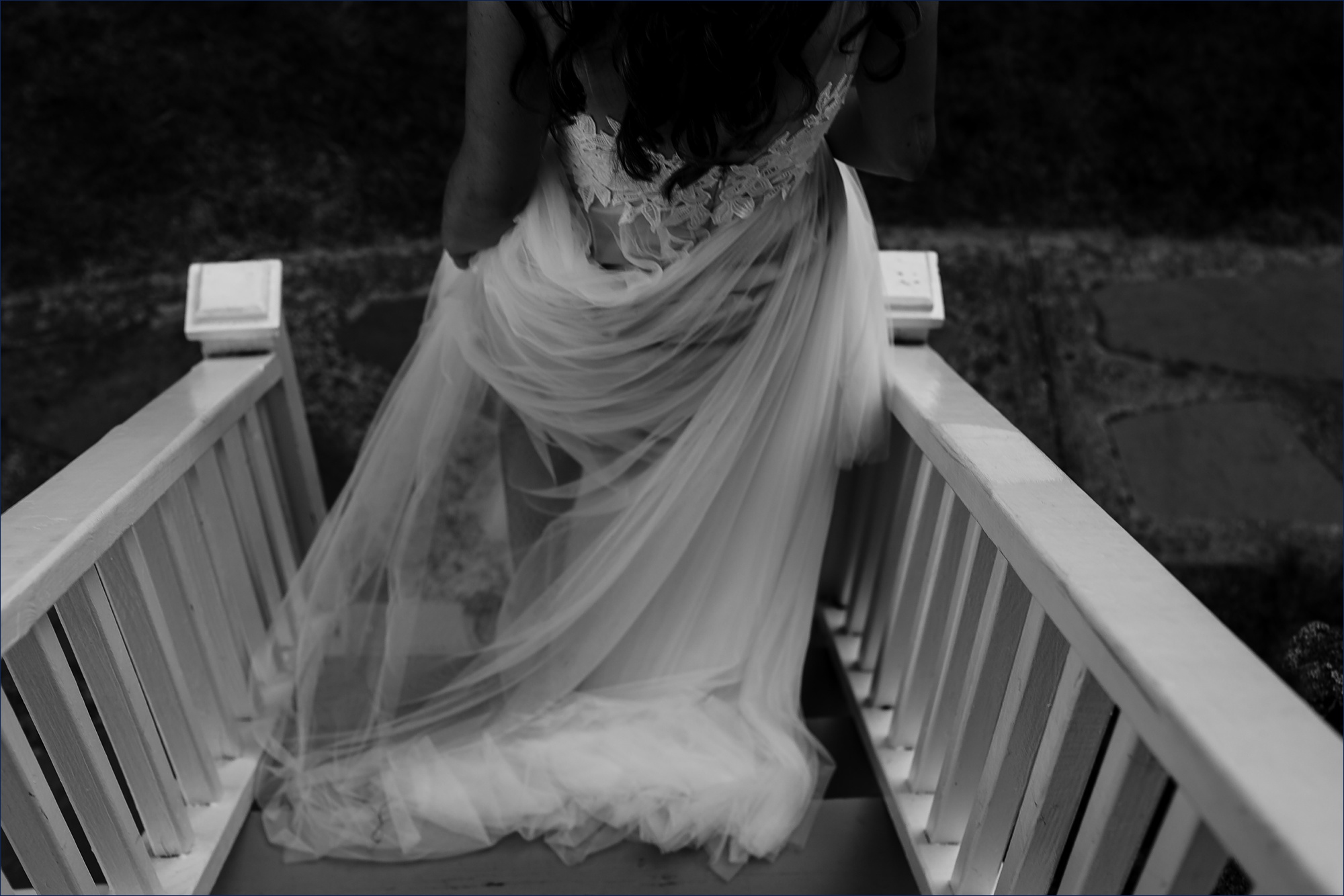 The bride in her tulle dress heads down the stairs to the wedding reception in Maine