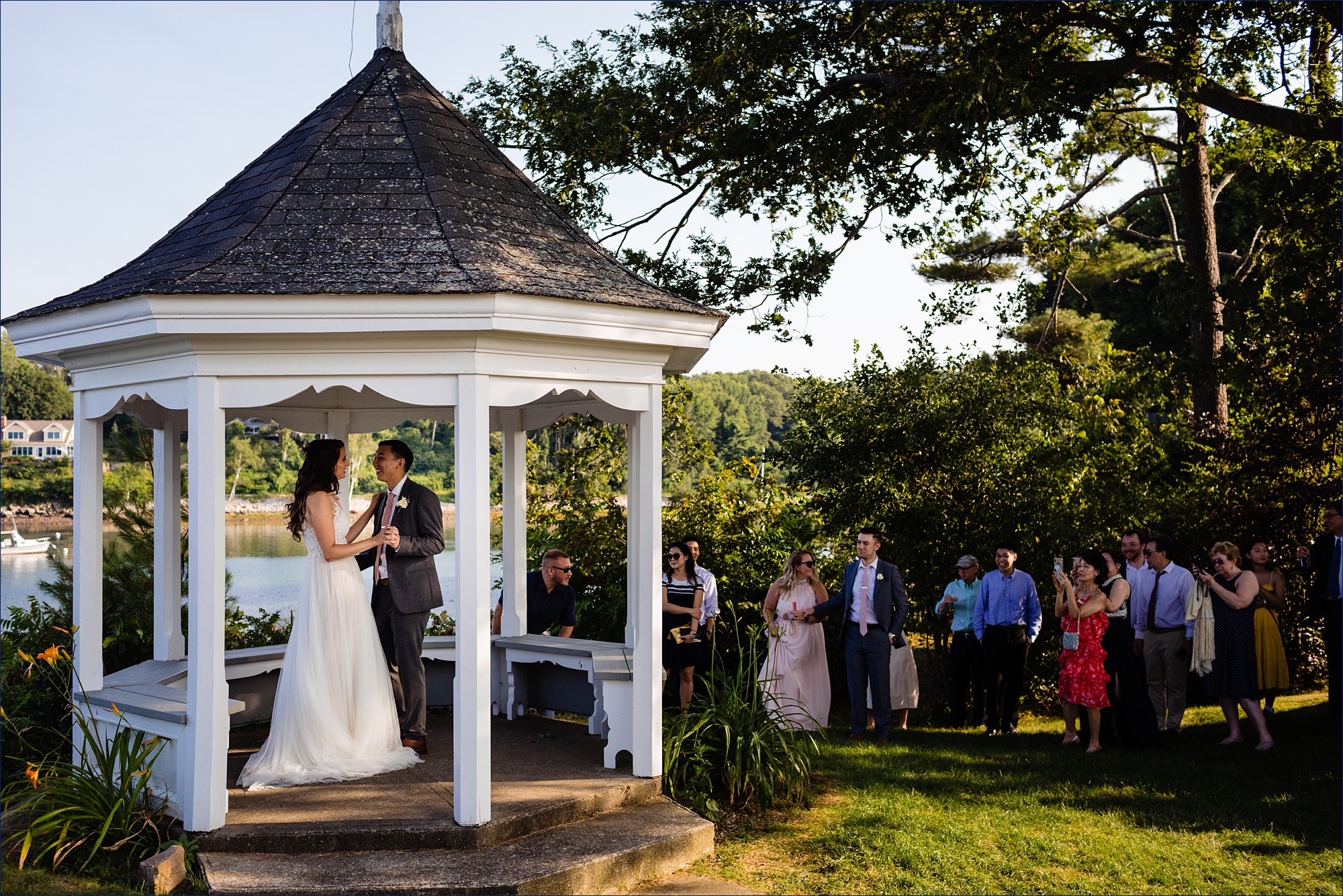 The bride and groom dance in the gazebo at York Dockside Guest Quarters with family cheering them on