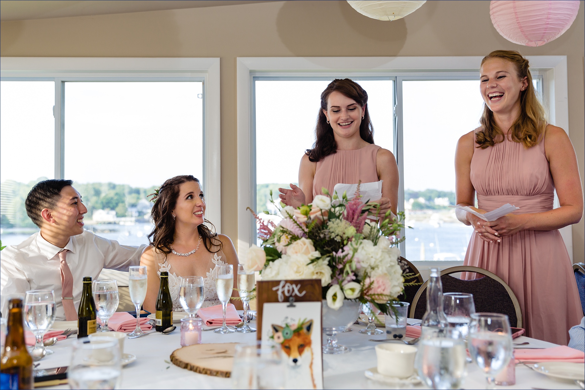 The maid of honor and a bridesmaid toast the newlyweds at their York Dockside Guest Quarters restaurant while they laugh