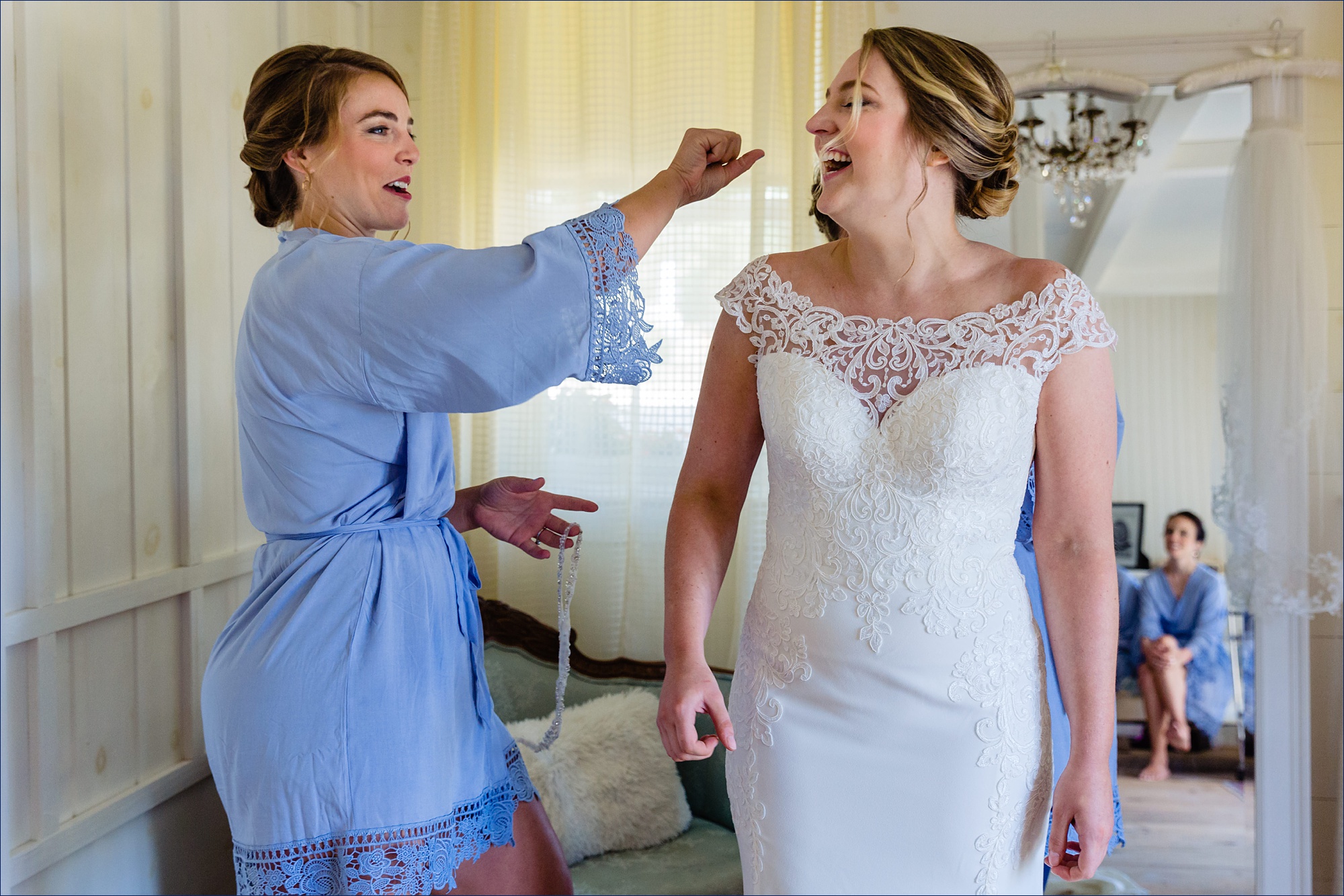 A bridesmaid plays around with the bride as she gets into her wedding gown at The Preserve in NH