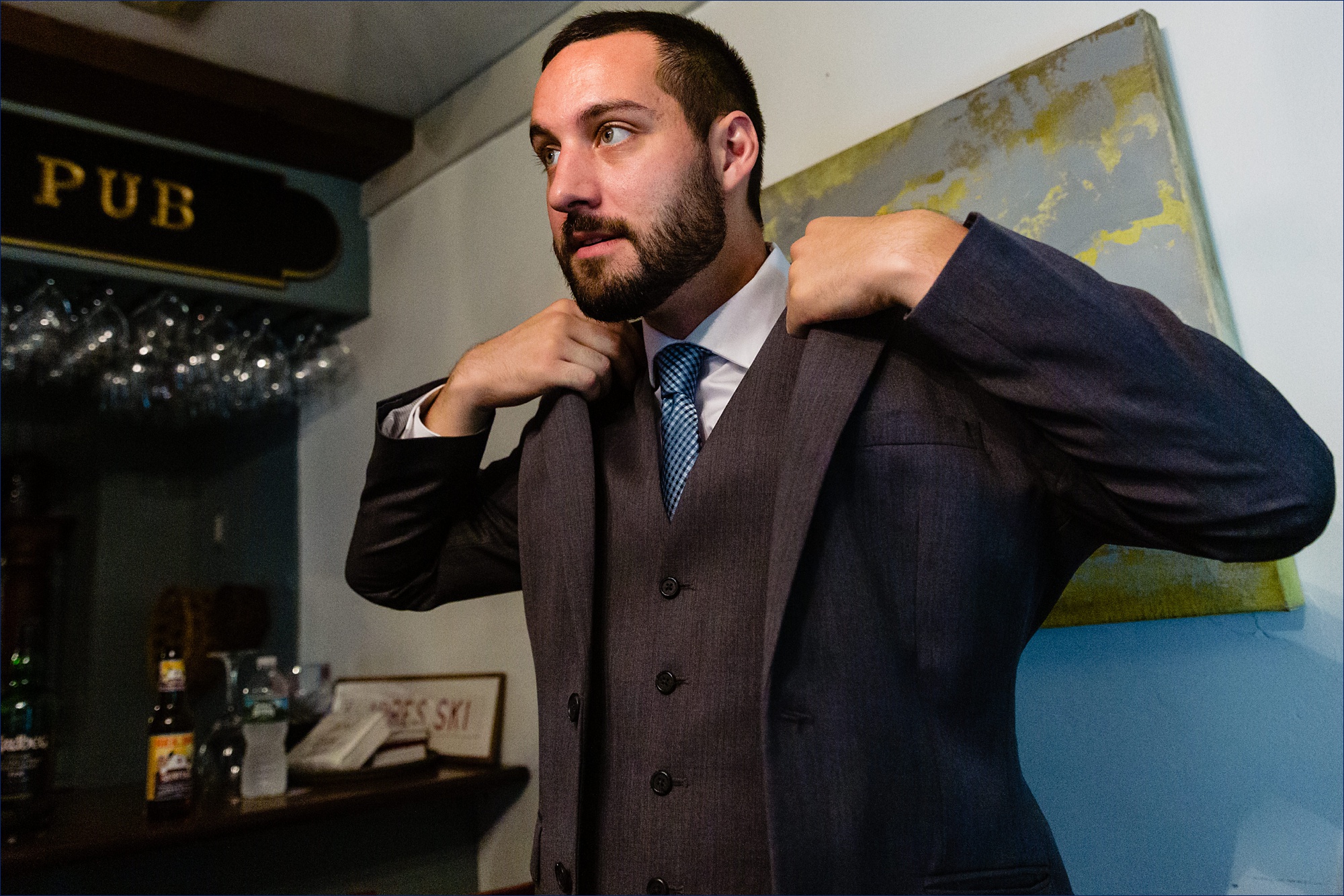 The groom gets ready for the wedding day by putting on his suit while hanging out in the pub