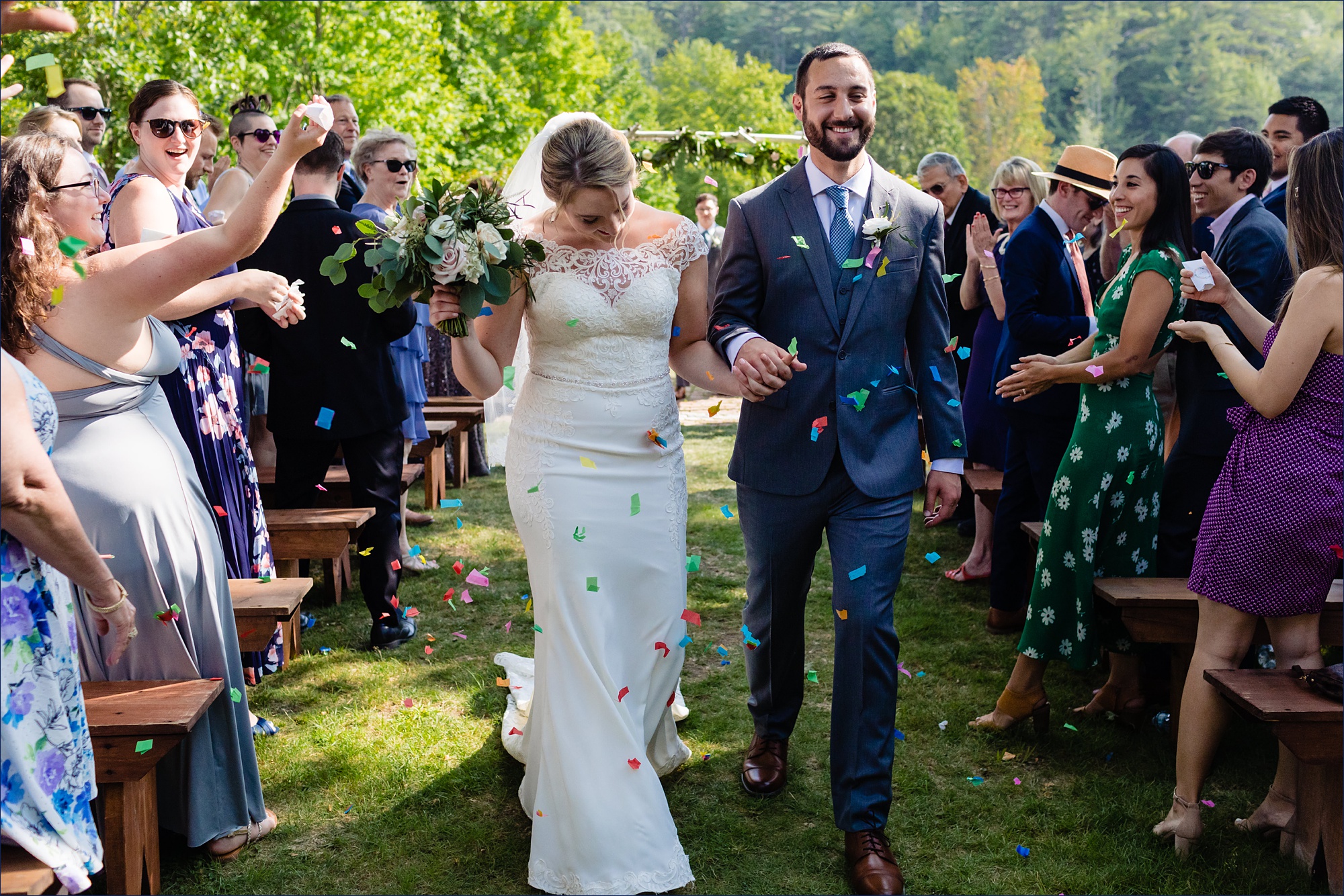 The bride and groom come back up the aisle to a shower of confetti after their outdoor wedding ceremony in NH