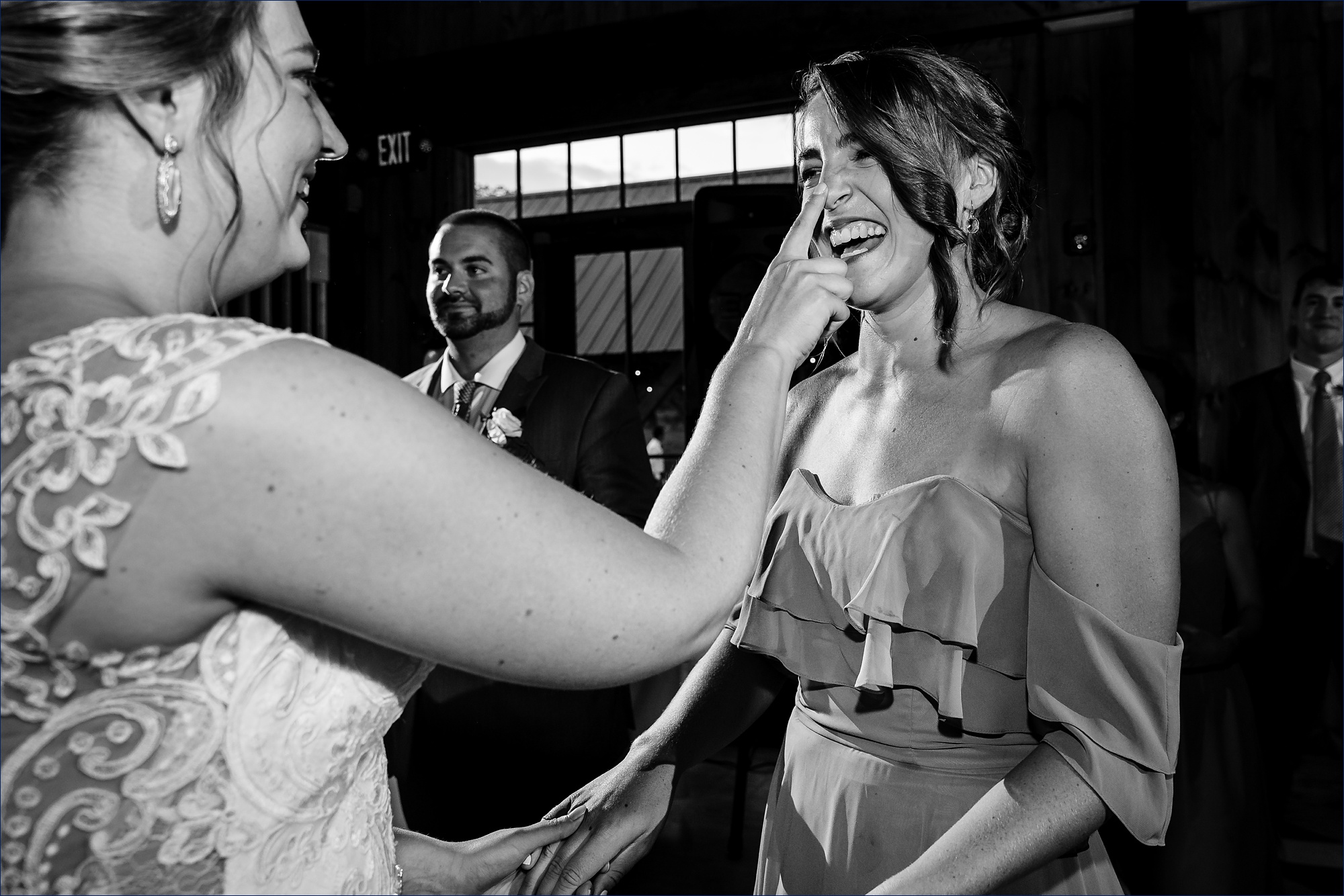 The bride boops her bridesmaid on the nose during her wedding reception in the barn at The Preserve in NH