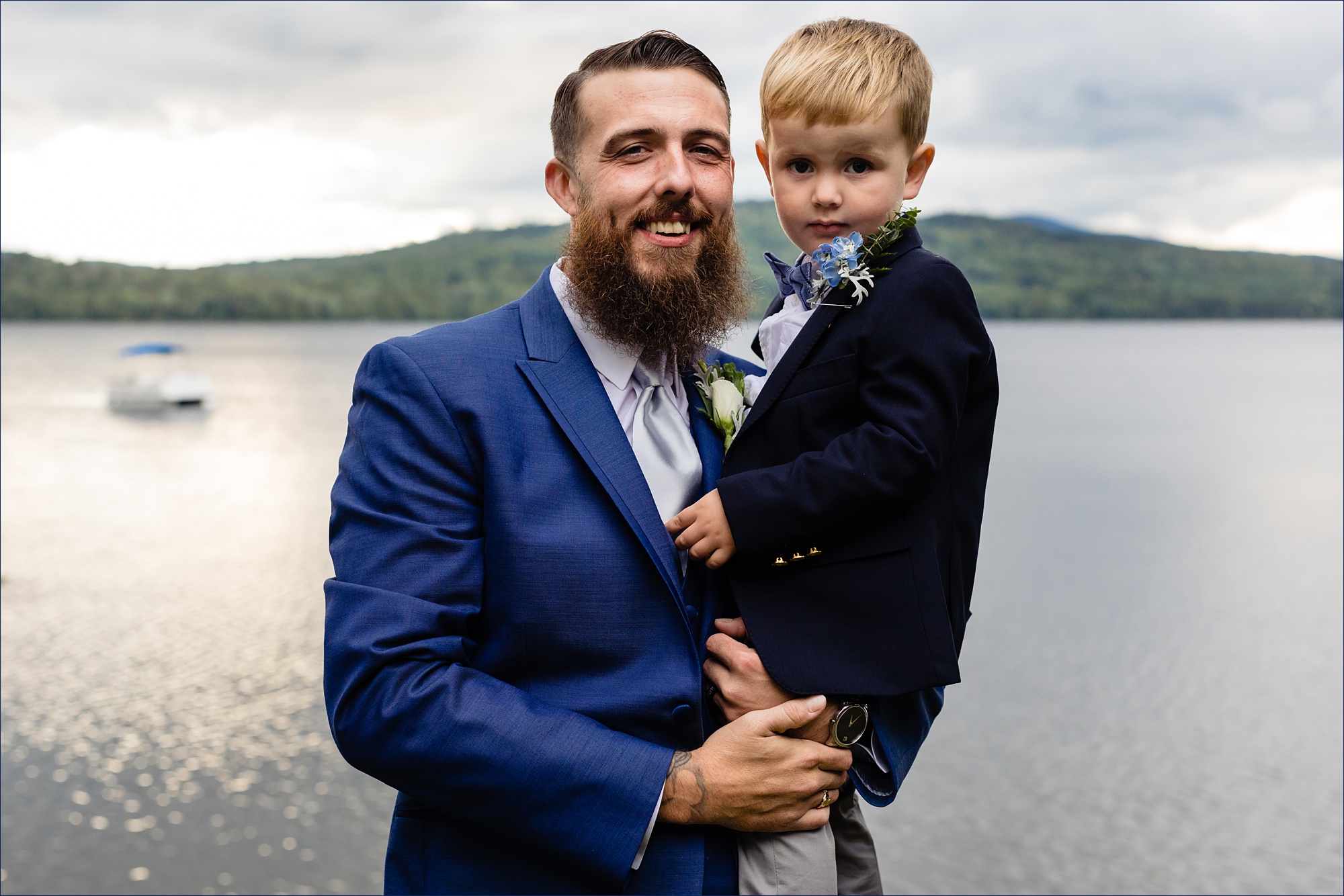 The groom and his son stand before the Maine lake and mountains