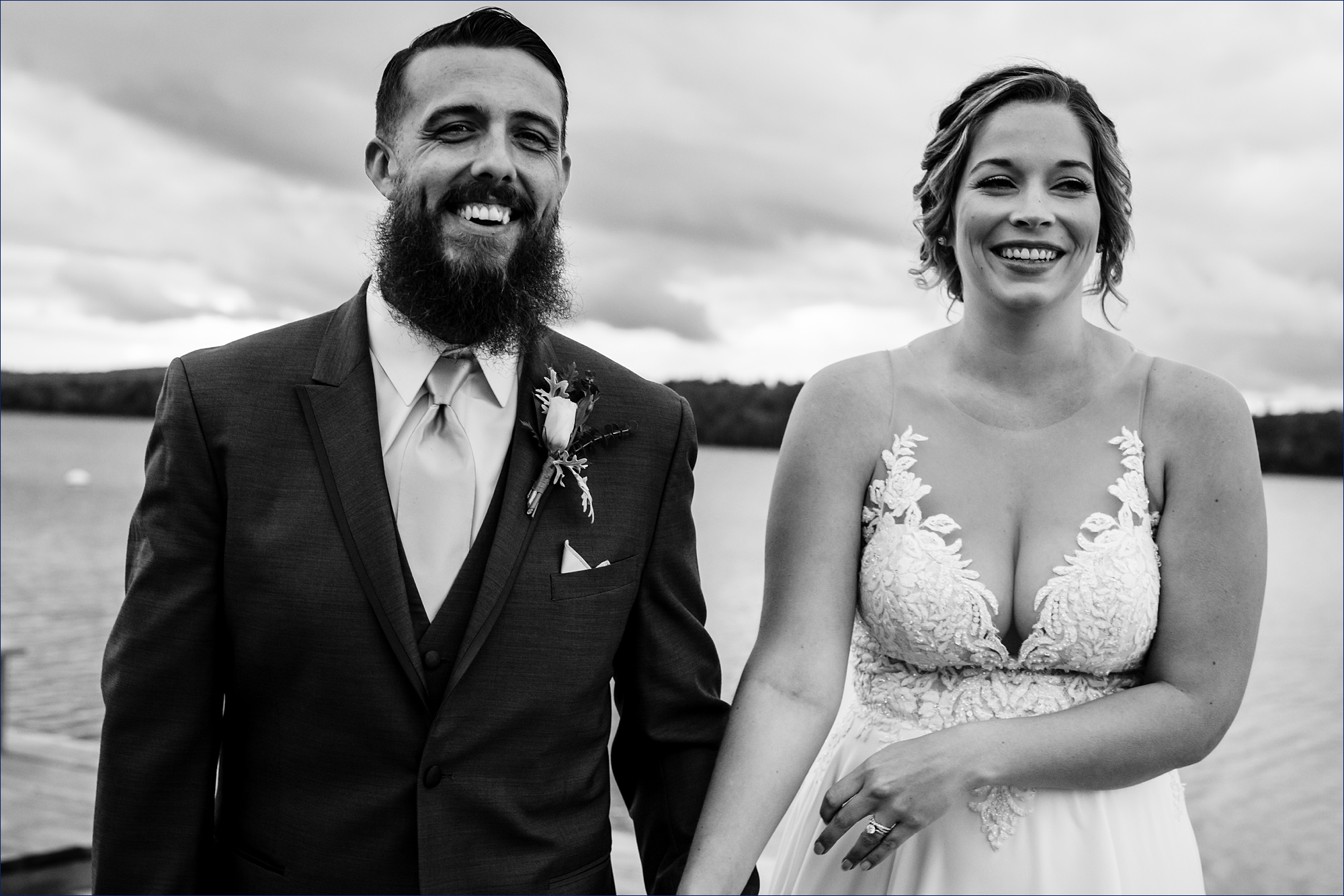 The bride and groom laugh while out by the lake at their Maine wedding