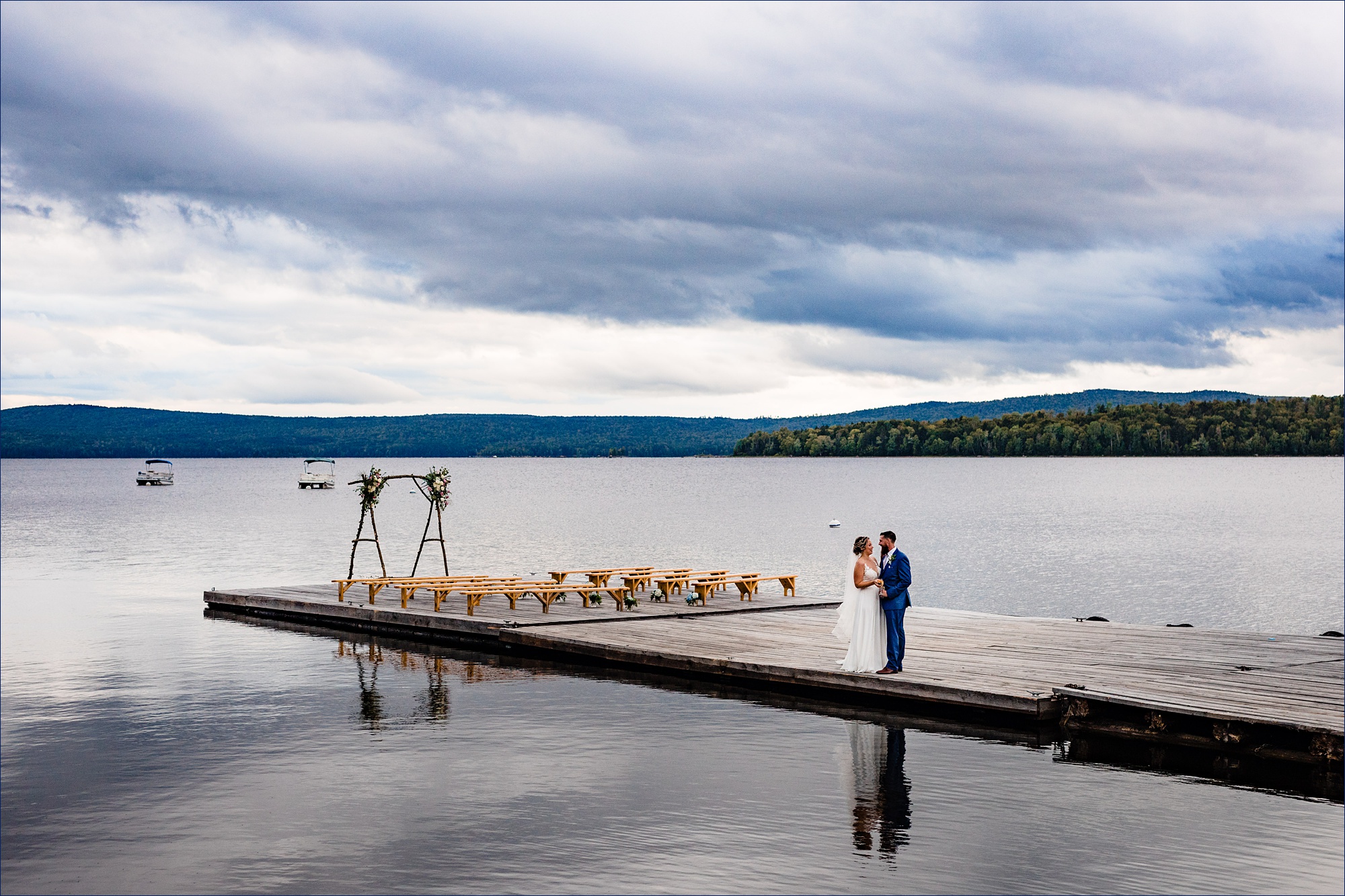 The bride and groom get close and take in a few quiet moments out on the docks in front of a Maine mountain range on their wedding day