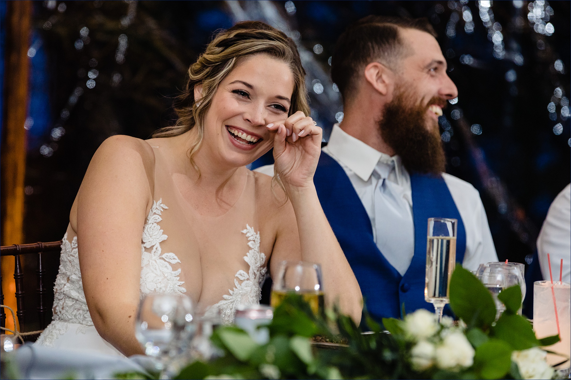 The newlyweds laugh at the toasts from friends on their wedding day