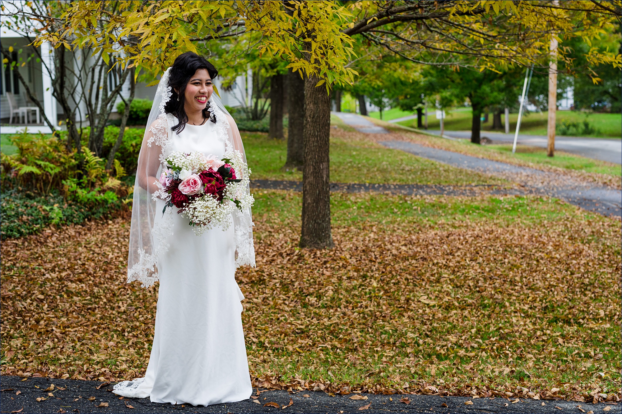 The bride stands in the fall leaves before heading to her Dartmouth Wedding ceremony