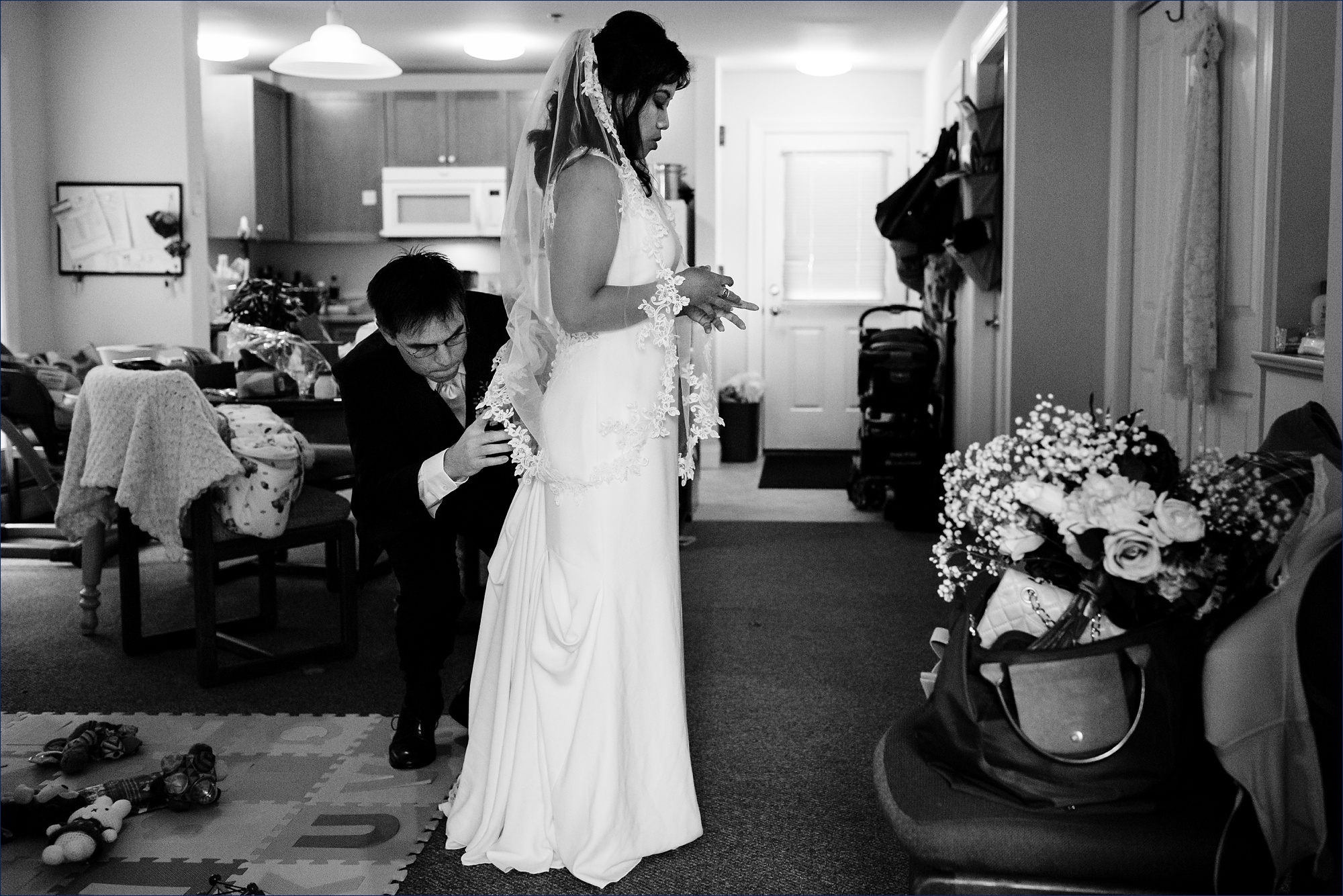 The groom helps get the bride's dress all secured before they head to the ceremony