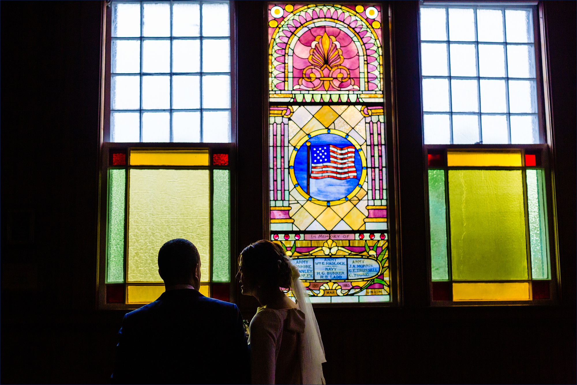 The bride and groom have a moment together in front of the stained glass windows of Islesford Congregational Church
