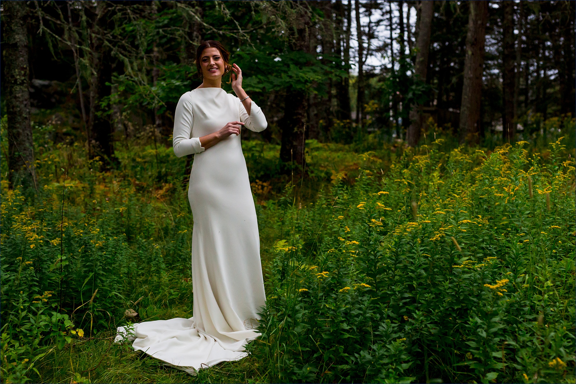 The stunning bride stands among the wildflowers and deep greens of Little Cranberry Island Maine on her wedding day
