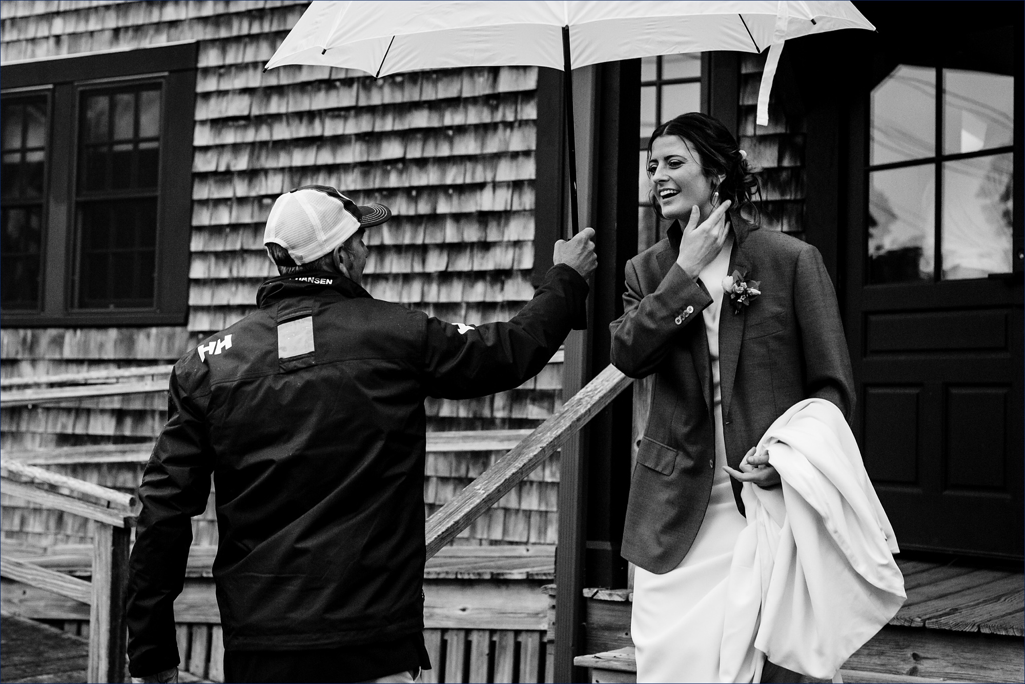 The bride throws on the groom's suit coat and gets a little help from a guest with an umbrella