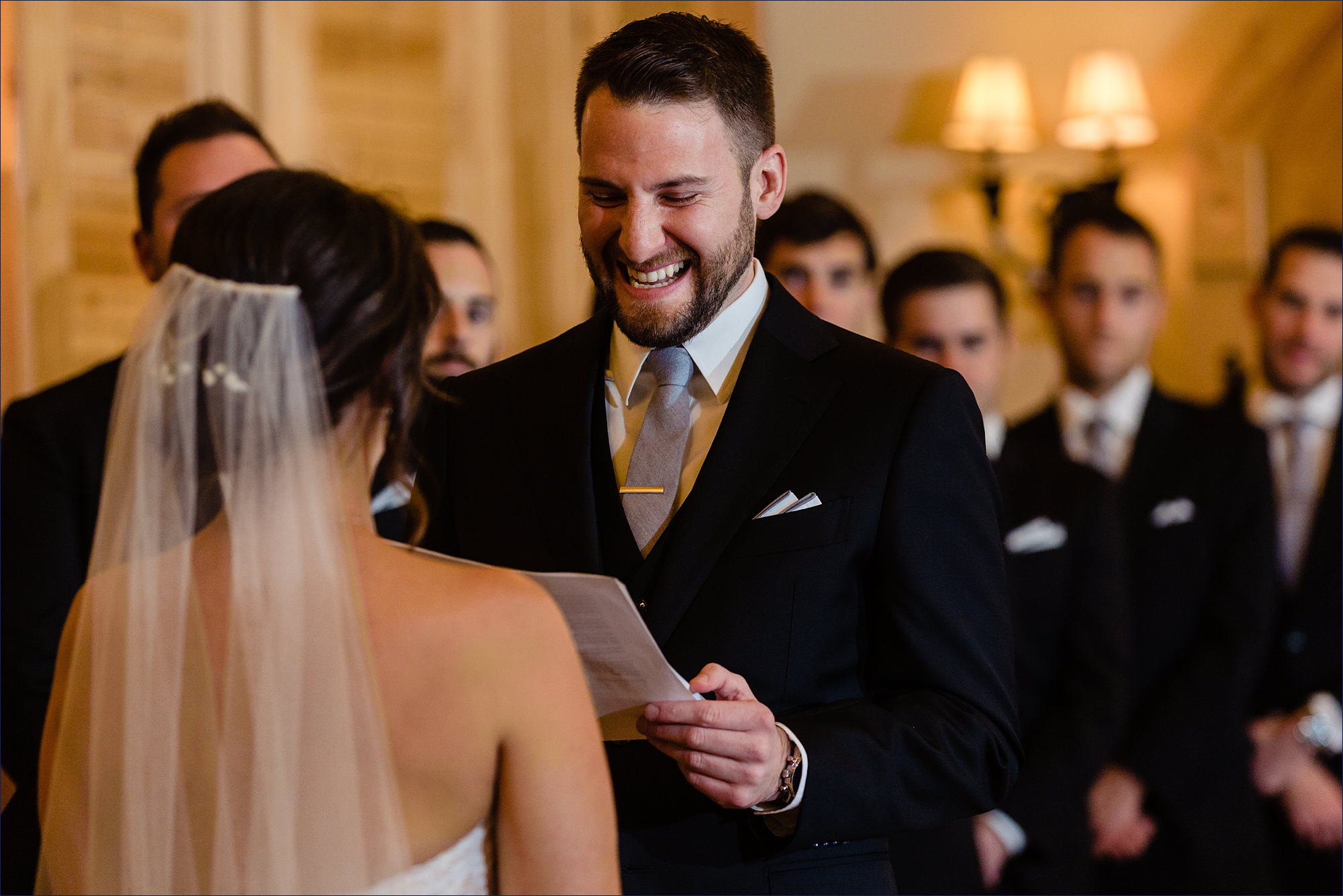 The groom laughs as he reads his vows to the bride at their wedding ceremony