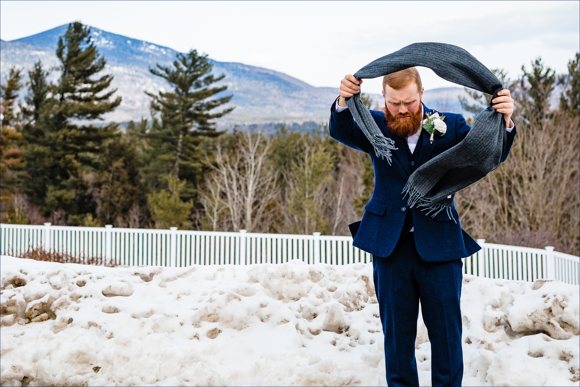 The groom fixes his tie in front of the White Mountains on his wedding day