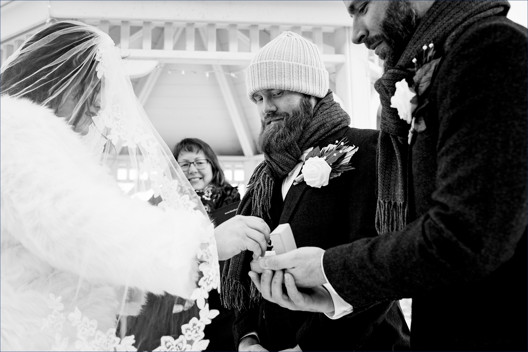 The groom watches as the best man hands over the wedding bands on his NH winter elopement