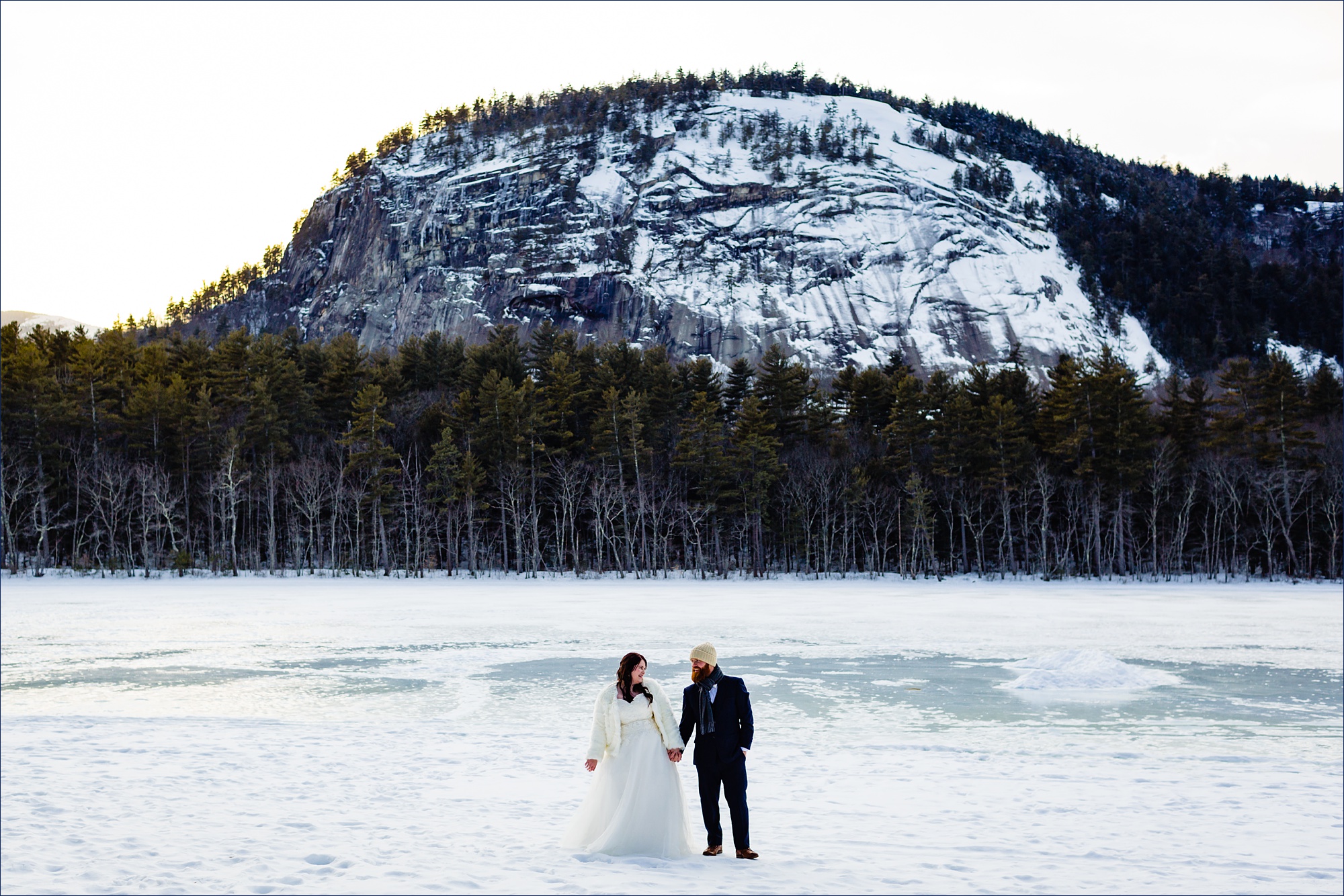 Echo Lake NH elopement with the couple standing in front of cathedral ledge in the winter
