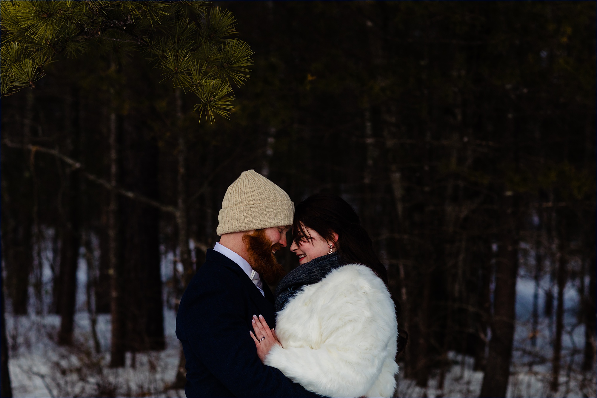 The bride and groom get close together in the wintery woods of NH